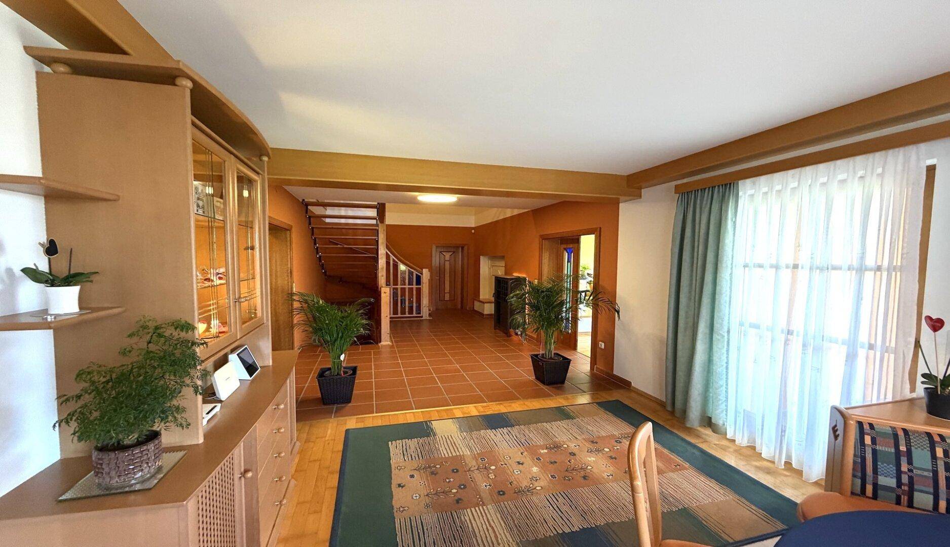 Geräumiger Flur mit Holztreppe, Fliesenboden und Zugang zu weiteren Räumen.