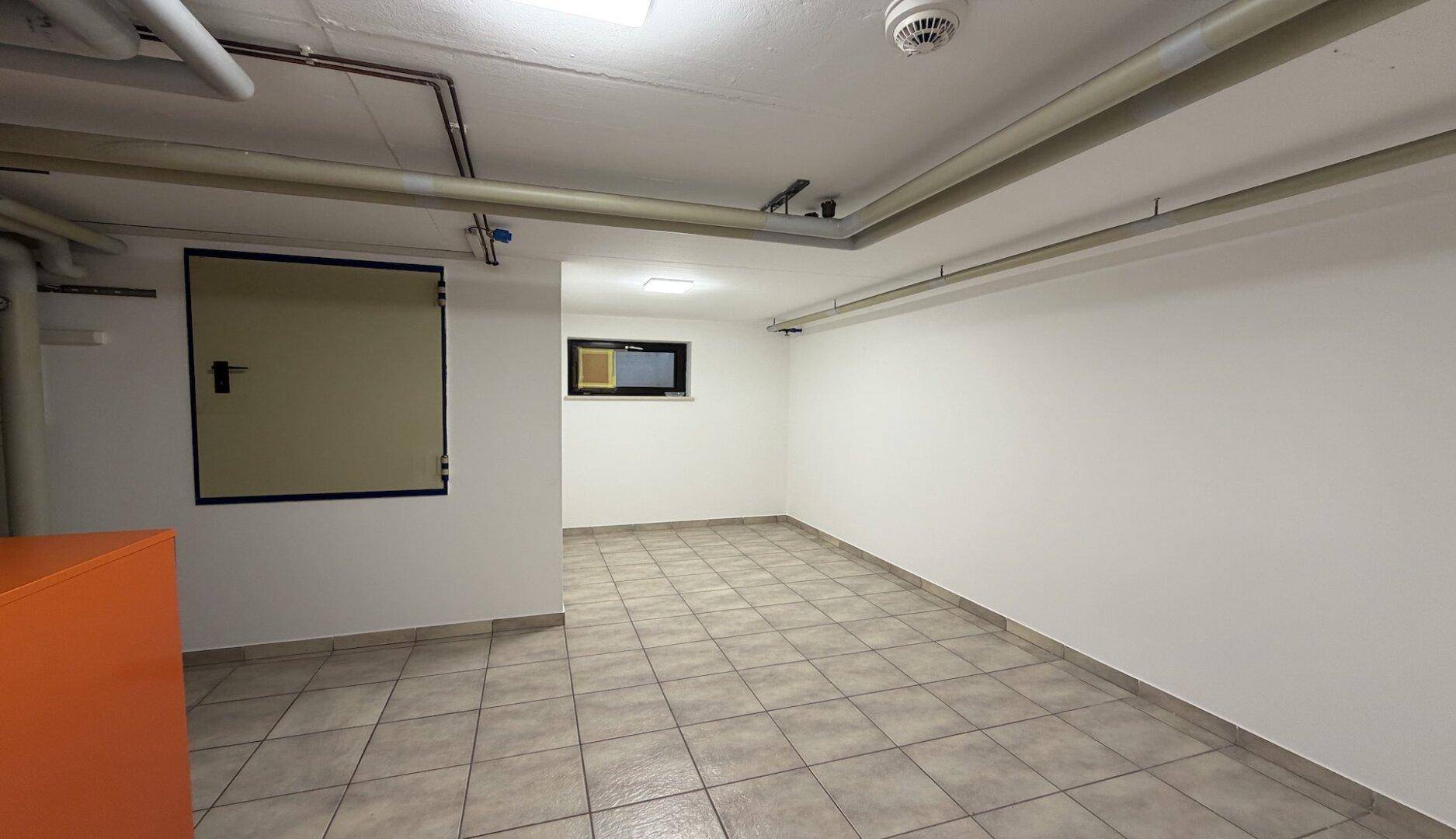 Heller Kellerraum mit Fliesenboden und kleinem Fenster, vielseitig nutzbar.