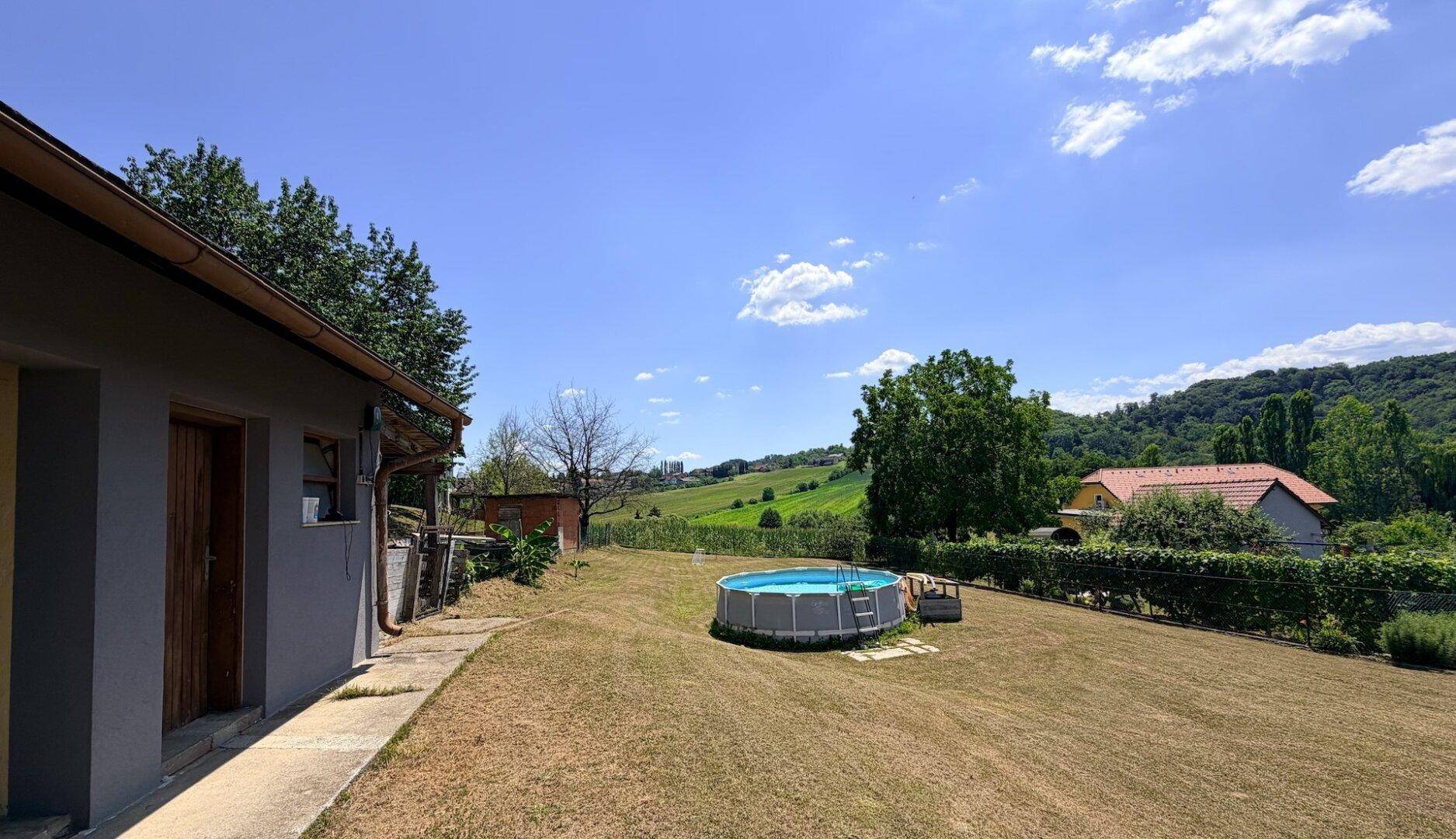 Weitläufiger Garten mit Aufstellpool und Panoramablick auf die umliegende Natur und Häuser.