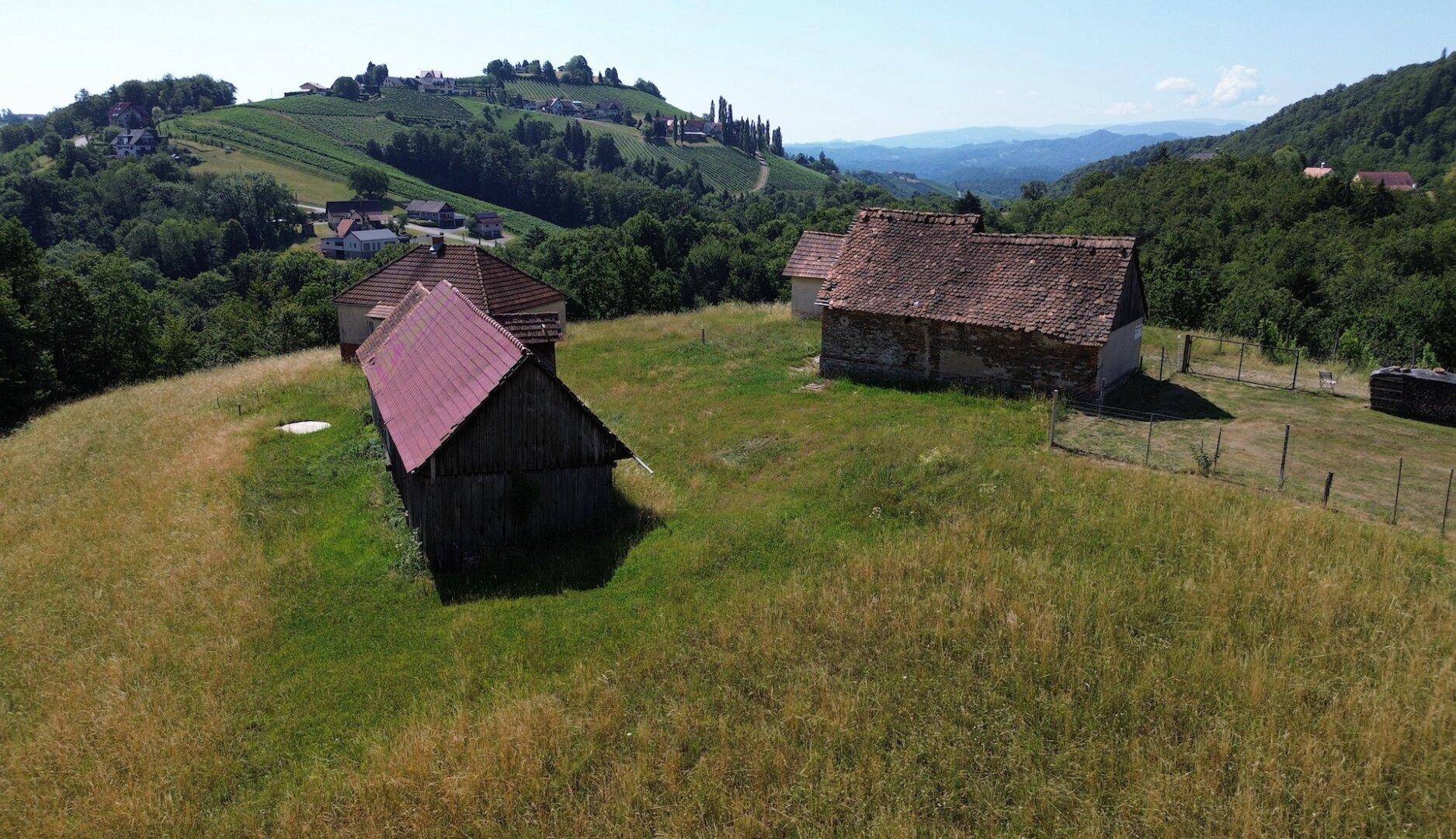 Weitwinkelaufnahme des Anwesens auf einem Hügel, mit Blick auf die weite, grüne Landschaft und die Weinberge.