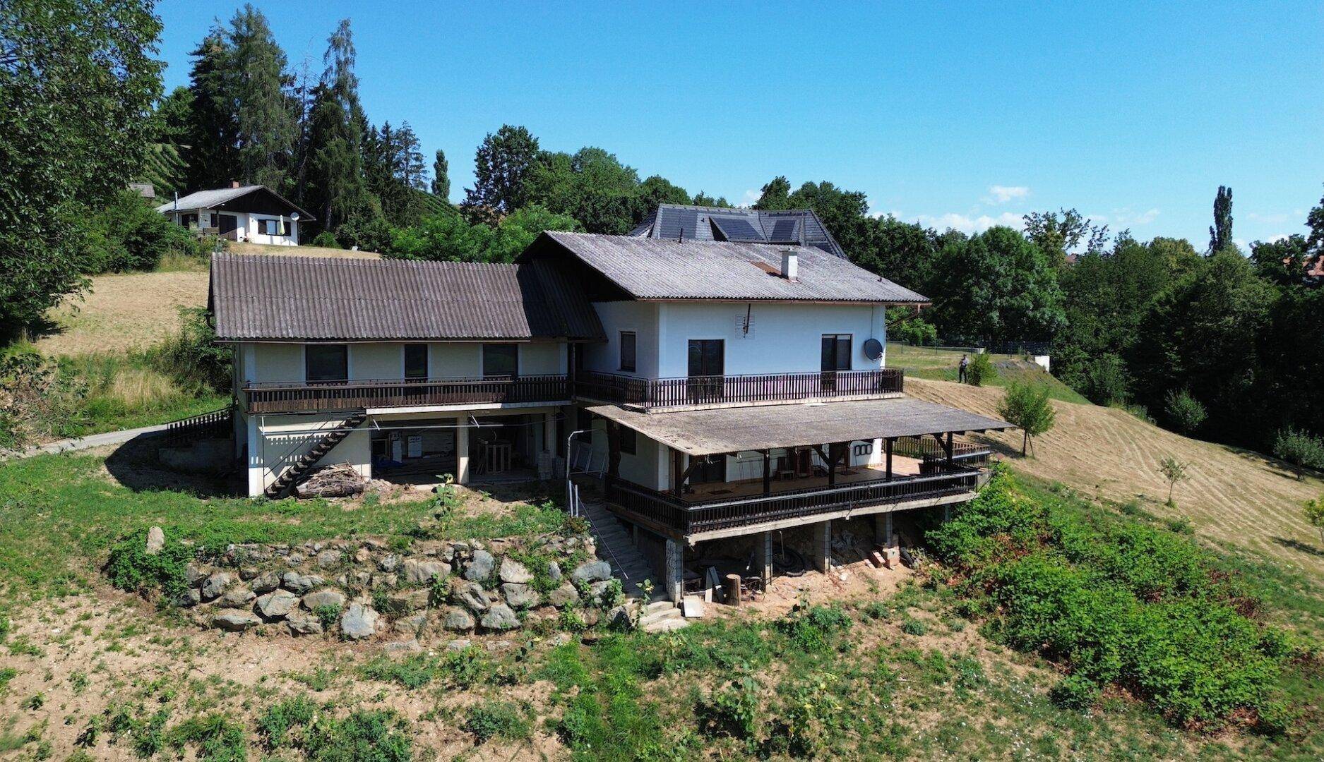 Das Haus in ländlicher Umgebung mit Terrassen und Balkonen, umgeben von viel Natur.