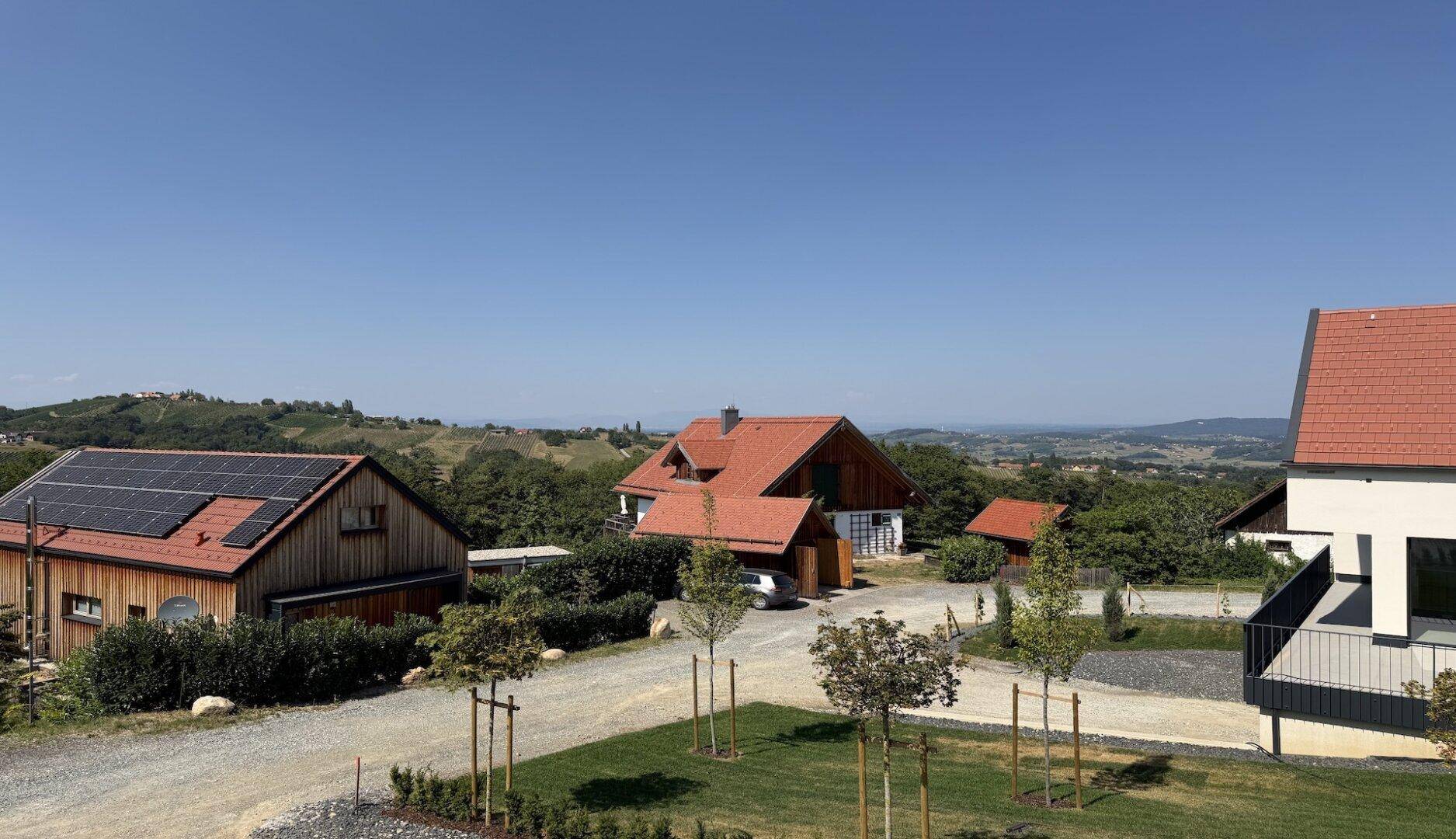 Panoramablick über die ländliche Umgebung mit grünen Hügeln, verstreuten Häusern und einem weiten Horizont.