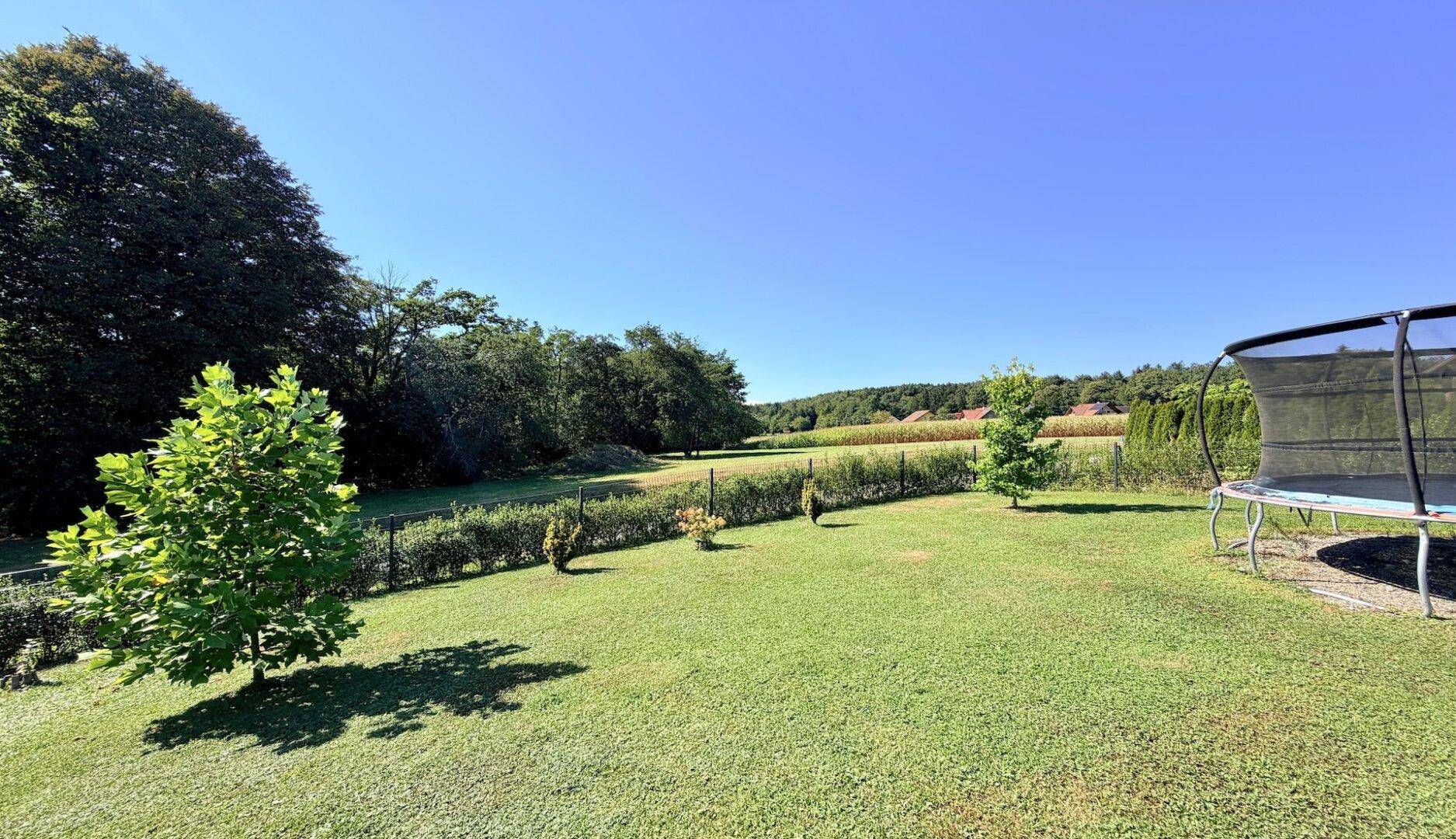 Weitläufiger Garten mit Rasenfläche und Blick auf die umliegende Landschaft und Felder.