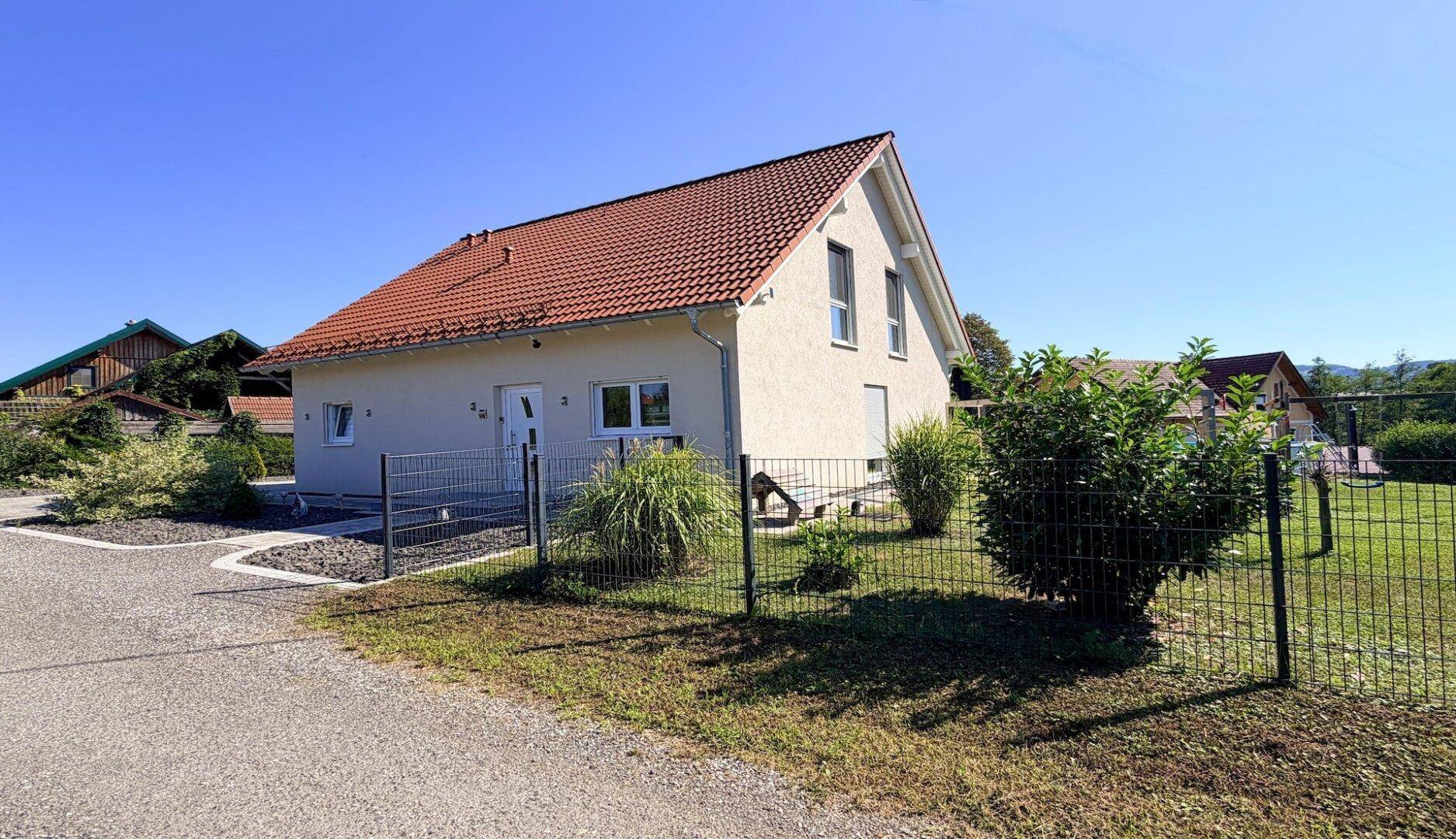 Modernes Einfamilienhaus mit heller Fassade, Satteldach und gepflegtem Vorgarten.