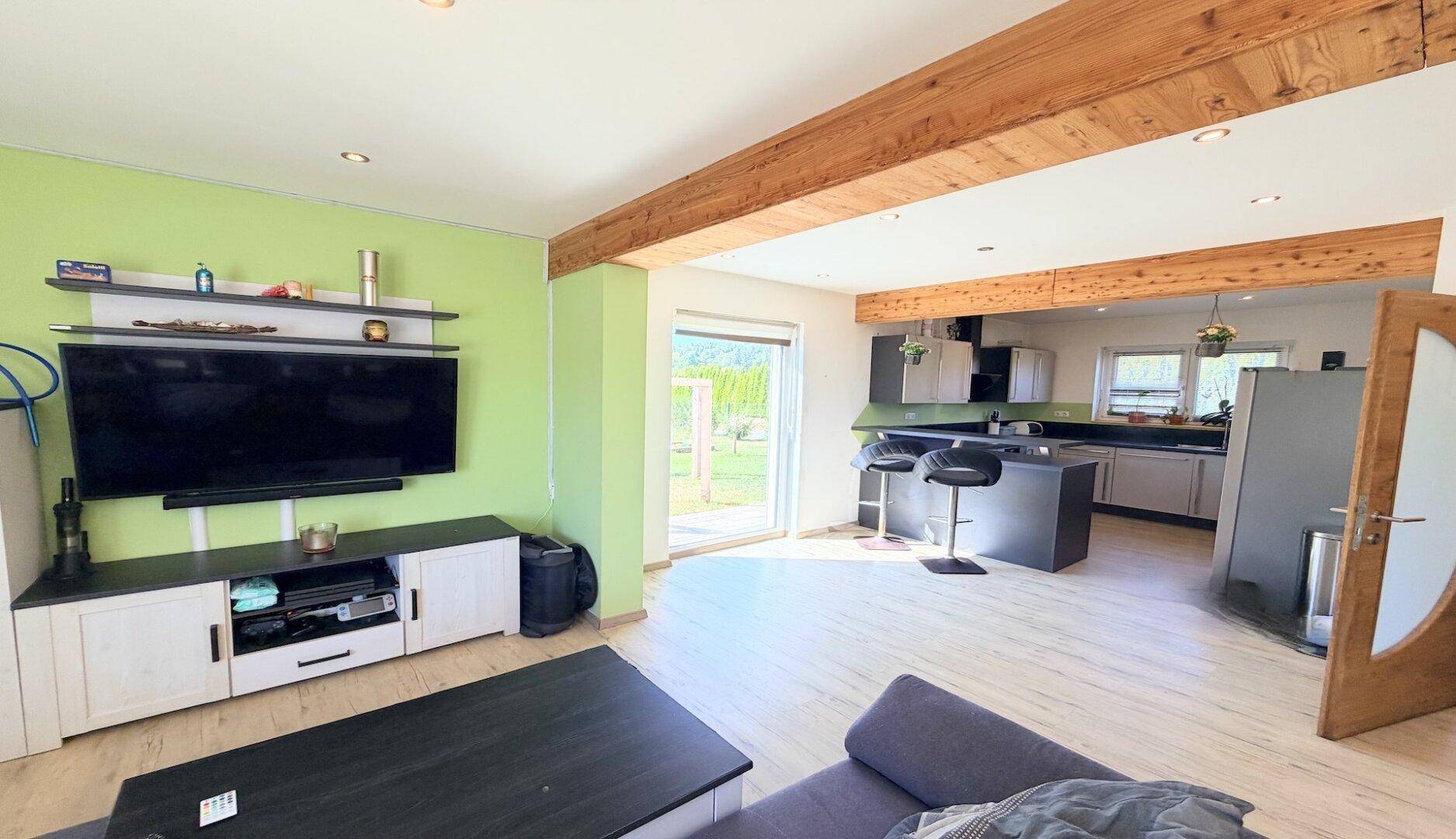 Offener Wohnbereich mit Sofa, Fernseher und direktem Zugang zur modernen Küche.