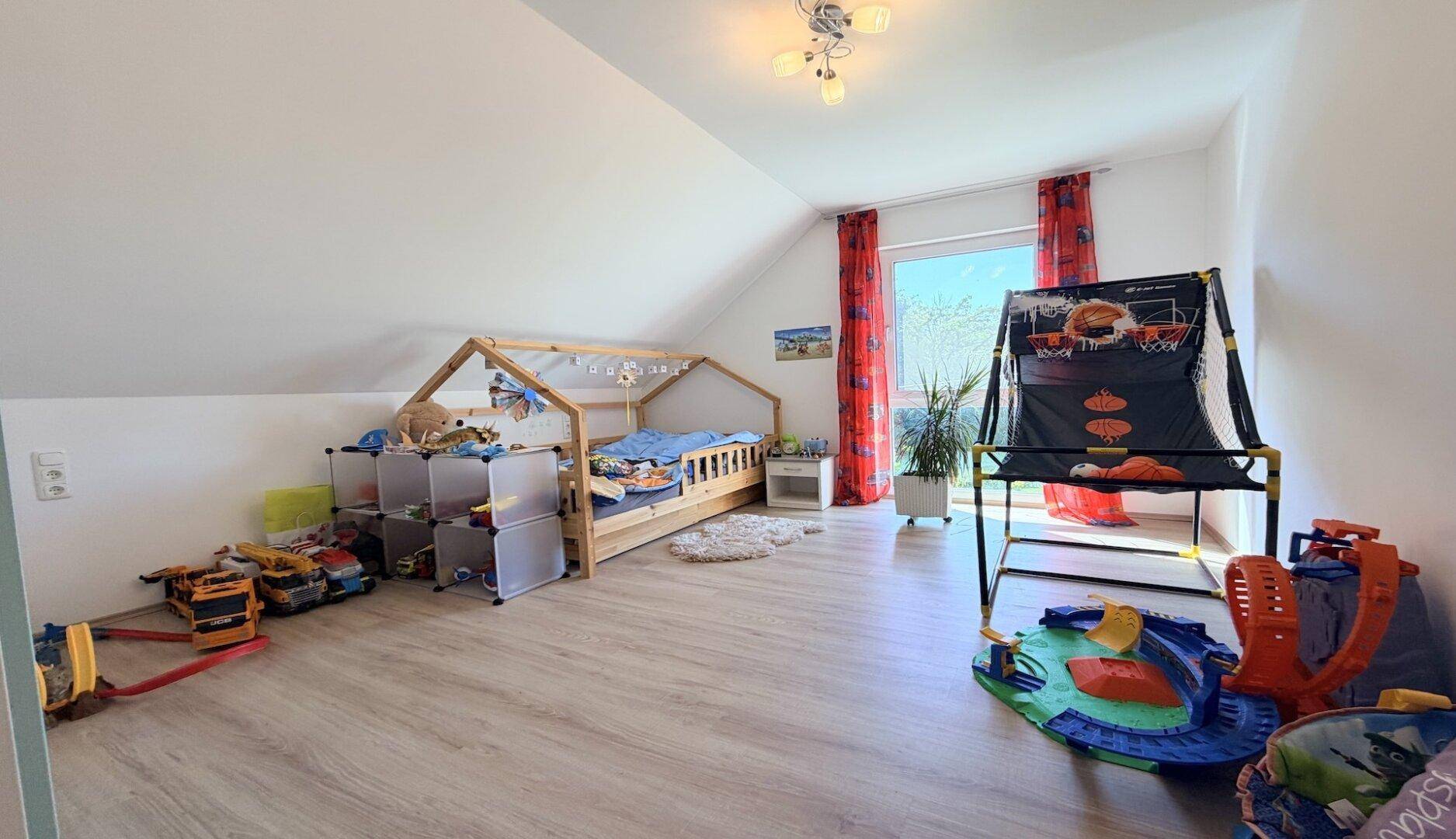 Helles Kinderzimmer im Dachgeschoss mit Spielzeug und Laminatboden.