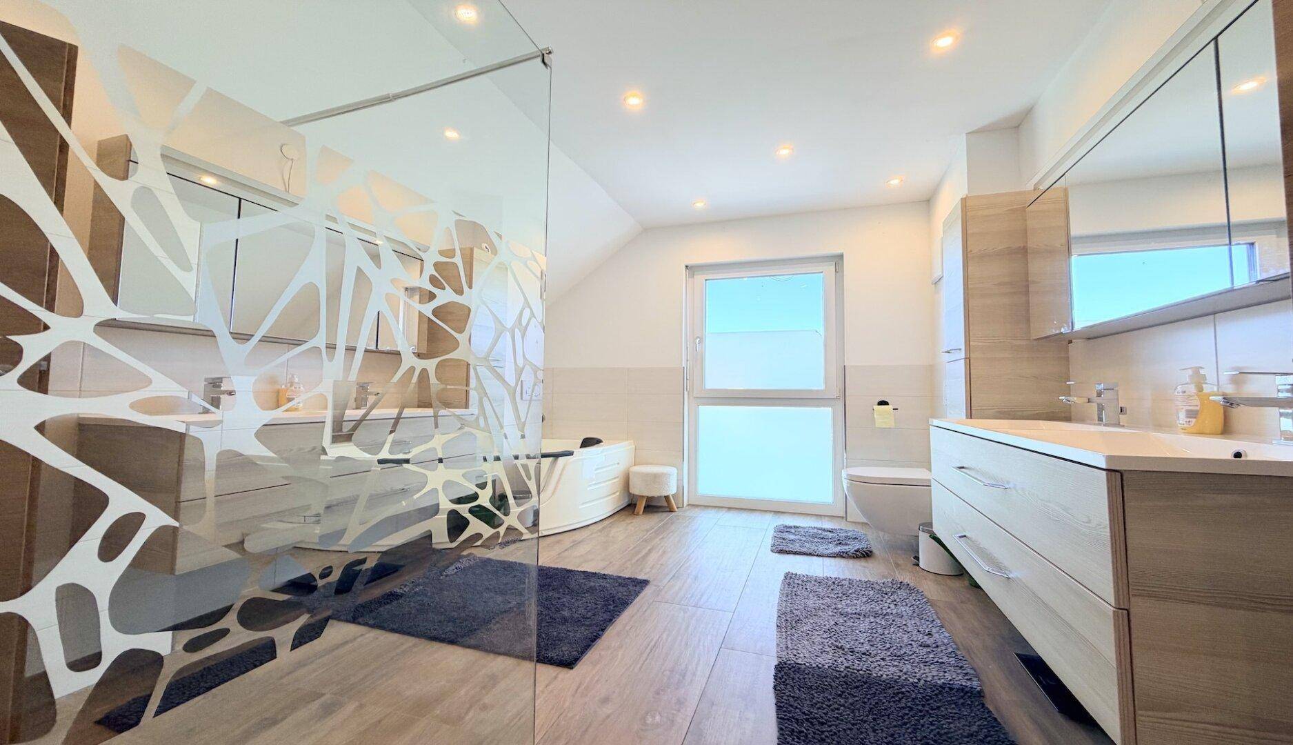 Modernes Badezimmer mit Eckbadewanne, Dusche und Doppelwaschbecken im Dachgeschoss.