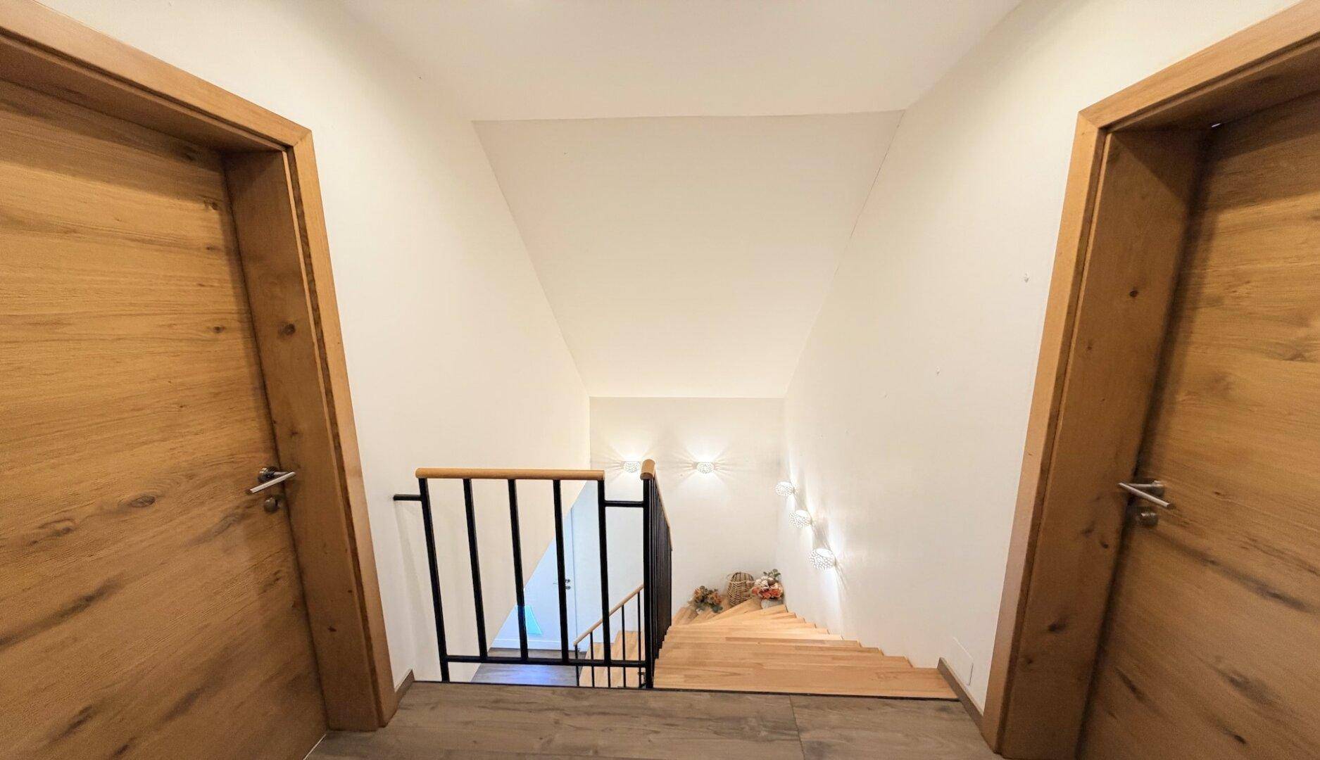 Oberer Flurbereich mit Holztüren und Blick auf die Treppe nach unten.