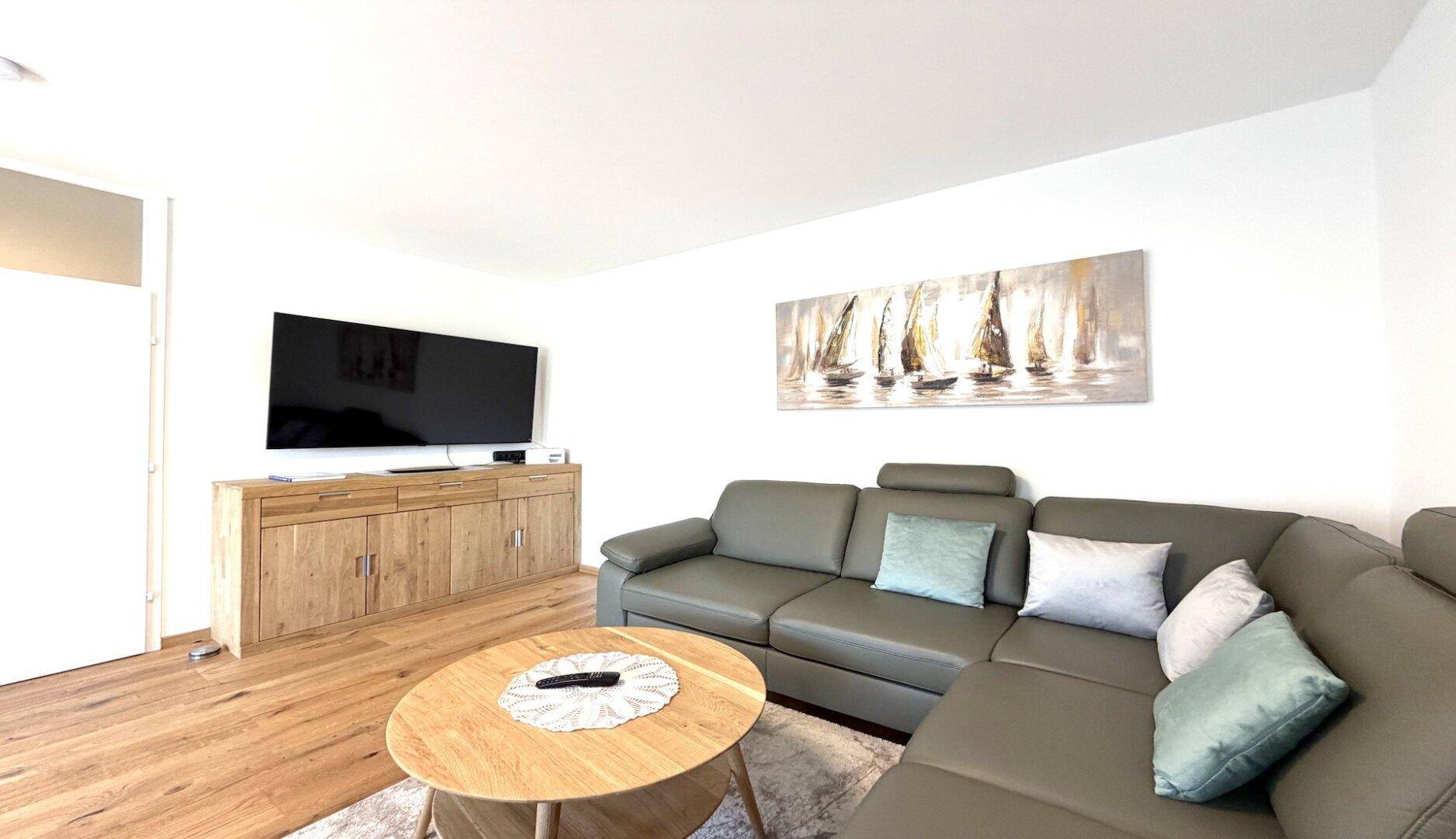 Gemütlicher Wohnbereich mit großem Ecksofa, Couchtisch und Wandfernseher.