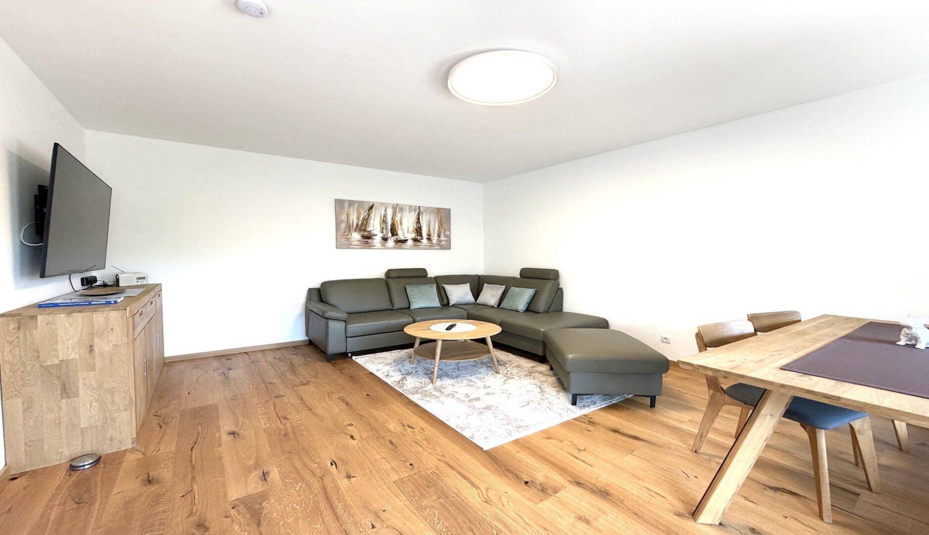 Geräumiger Wohn- und Essbereich mit bequemer Sitzecke, Esstisch und Holzboden.