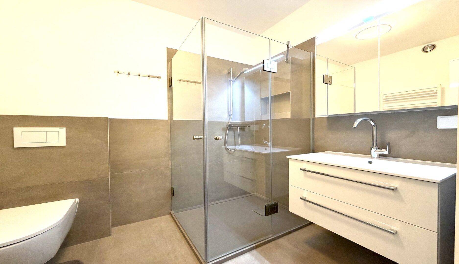 Modernes Badezimmer mit ebenerdiger Dusche, Waschtisch und Wand-WC.