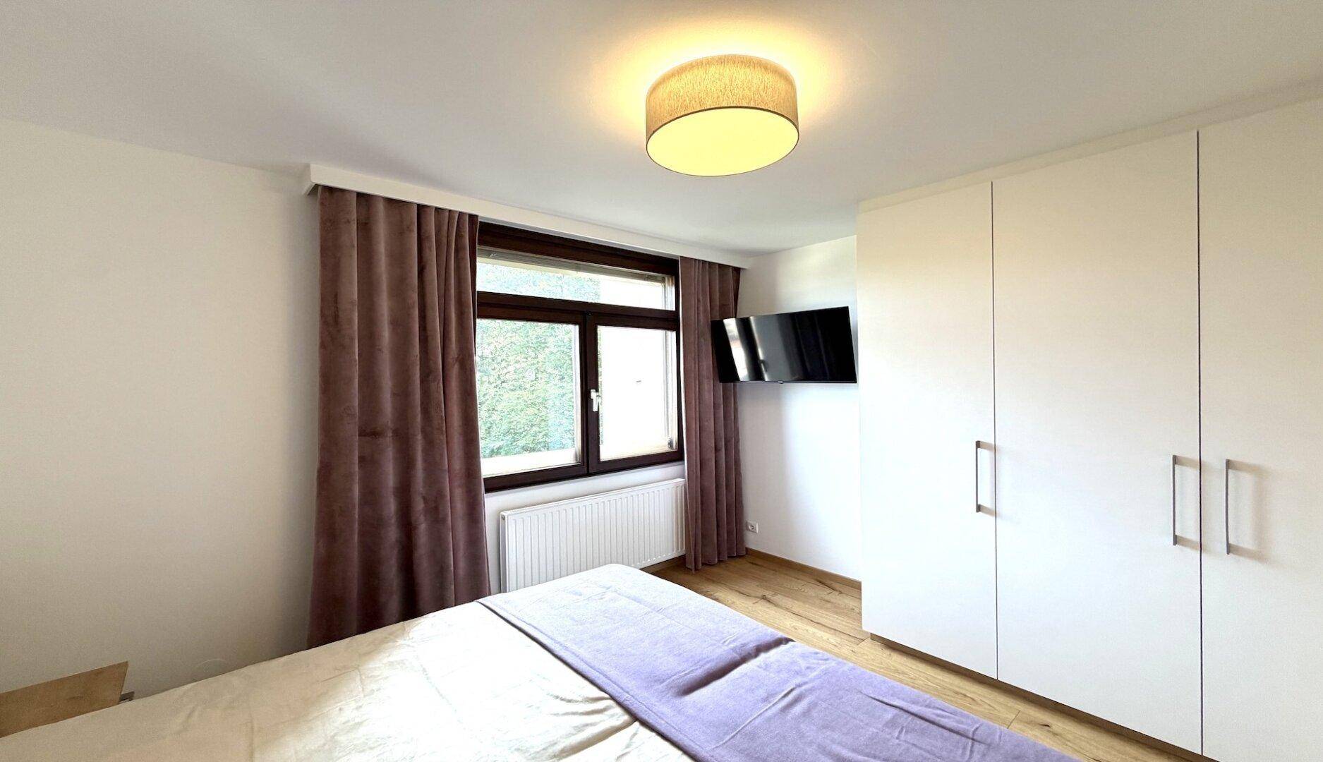 Schlafzimmer mit Einbauschränken, Doppelbett und Fernseher an der Wand.
