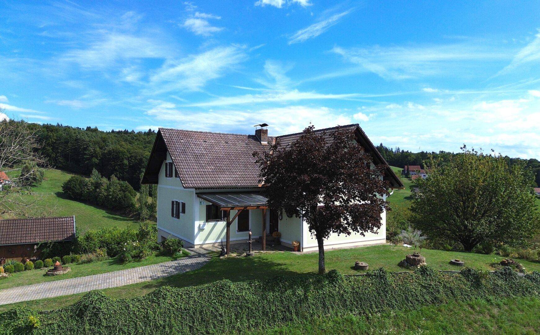 Charmantes Einfamilienhaus mit Satteldach und gepflegtem Garten in idyllischer Hügellandschaft.