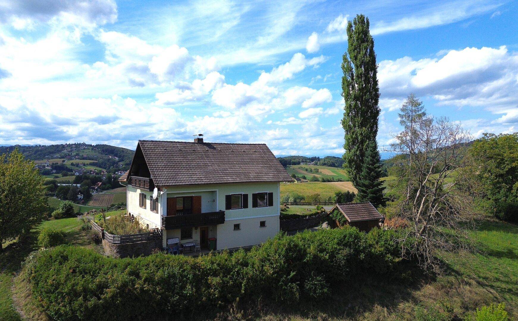 Haus mit Balkon und Satteldach in einer malerischen ländlichen Umgebung mit weiten Ausblicken.