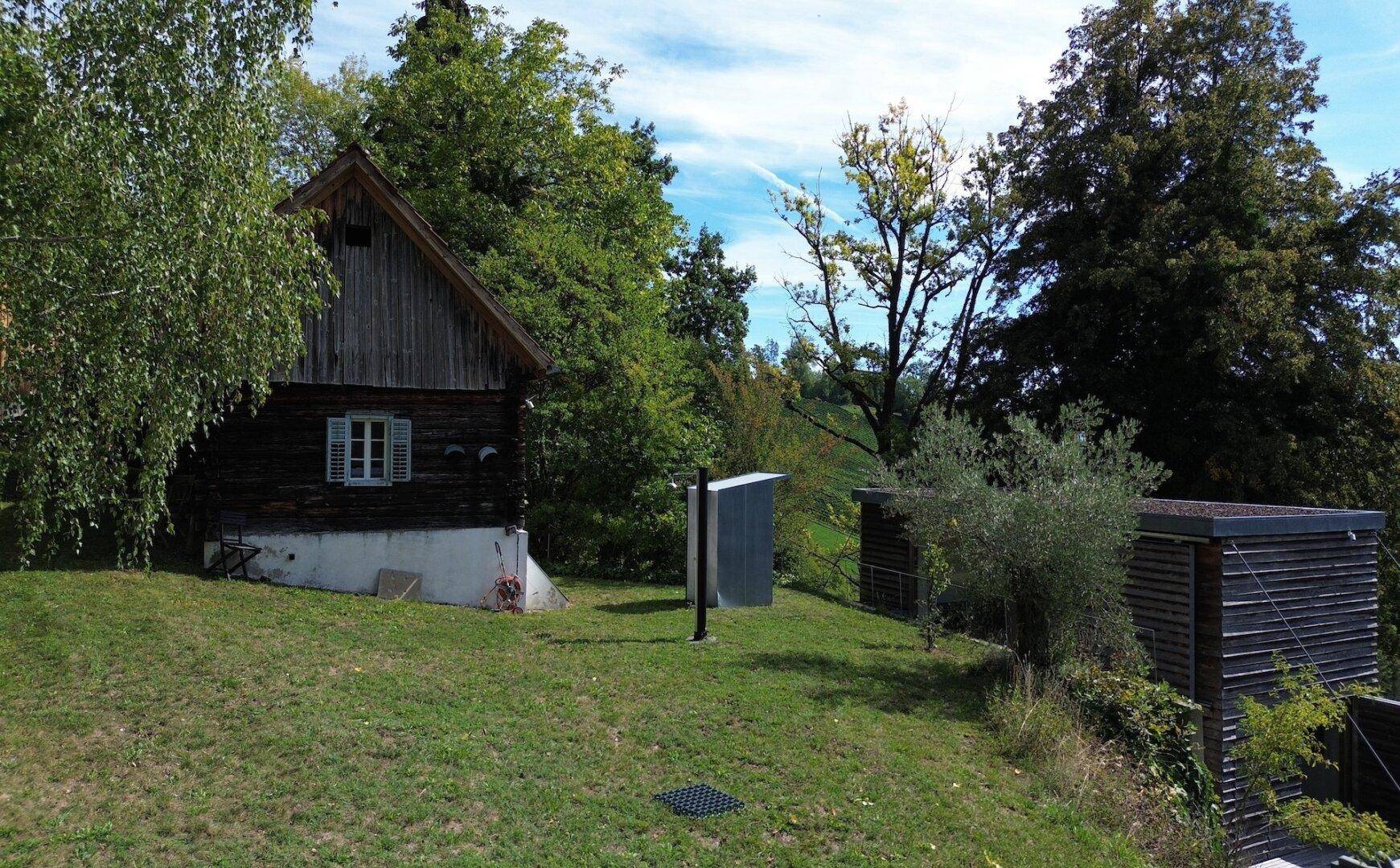 Seitenansicht eines traditionellen Holzhauses mit weißem Fensterladen und grüner Umgebung.