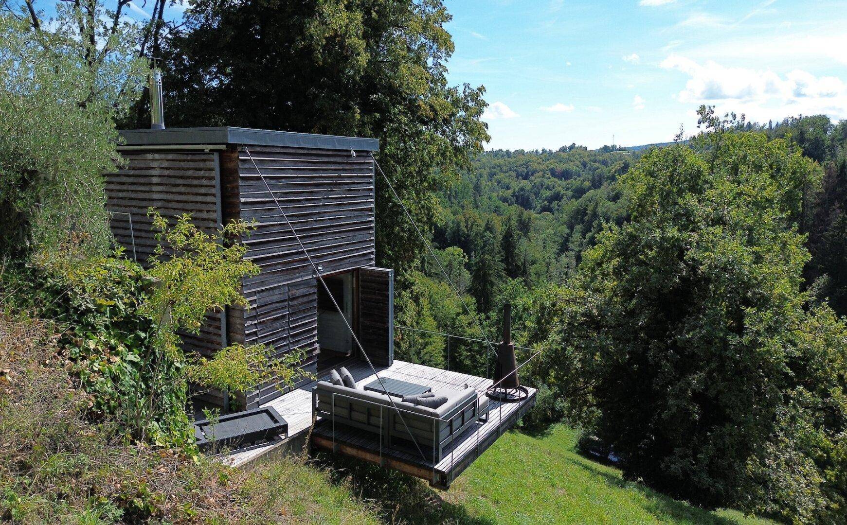 Moderne Holzfassade des Hauses mit großer Terrasse und weitem Blick ins Grüne.
