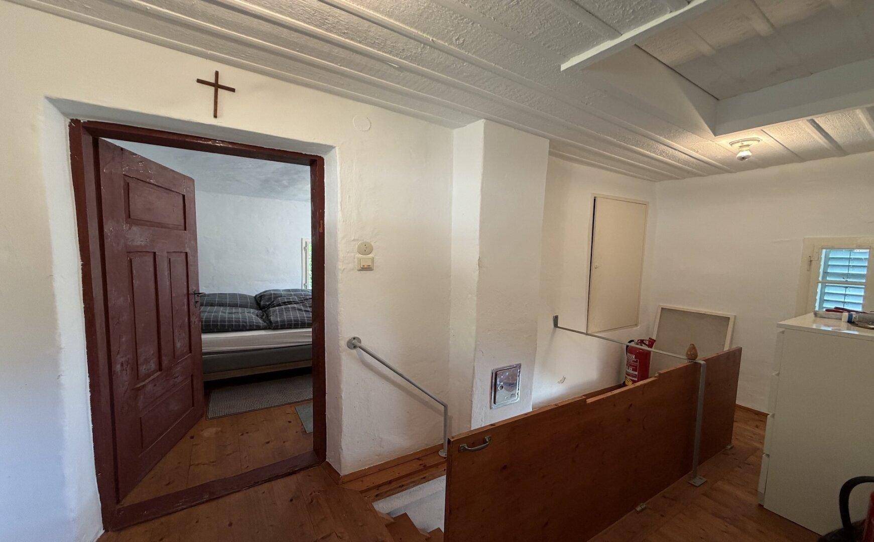 Rustikaler Flur im alten Haus mit Holzboden, Treppe und Zugang zu einem Schlafzimmer.