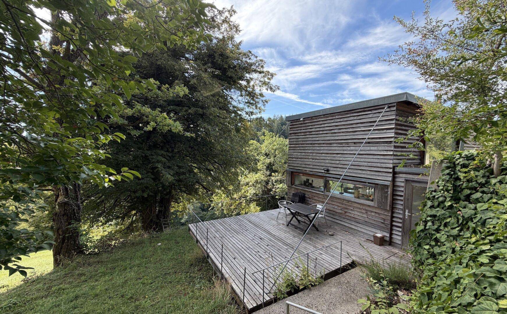 Moderne Holzfassade des Hauses mit großer Holzterrasse und Blick auf die Natur.