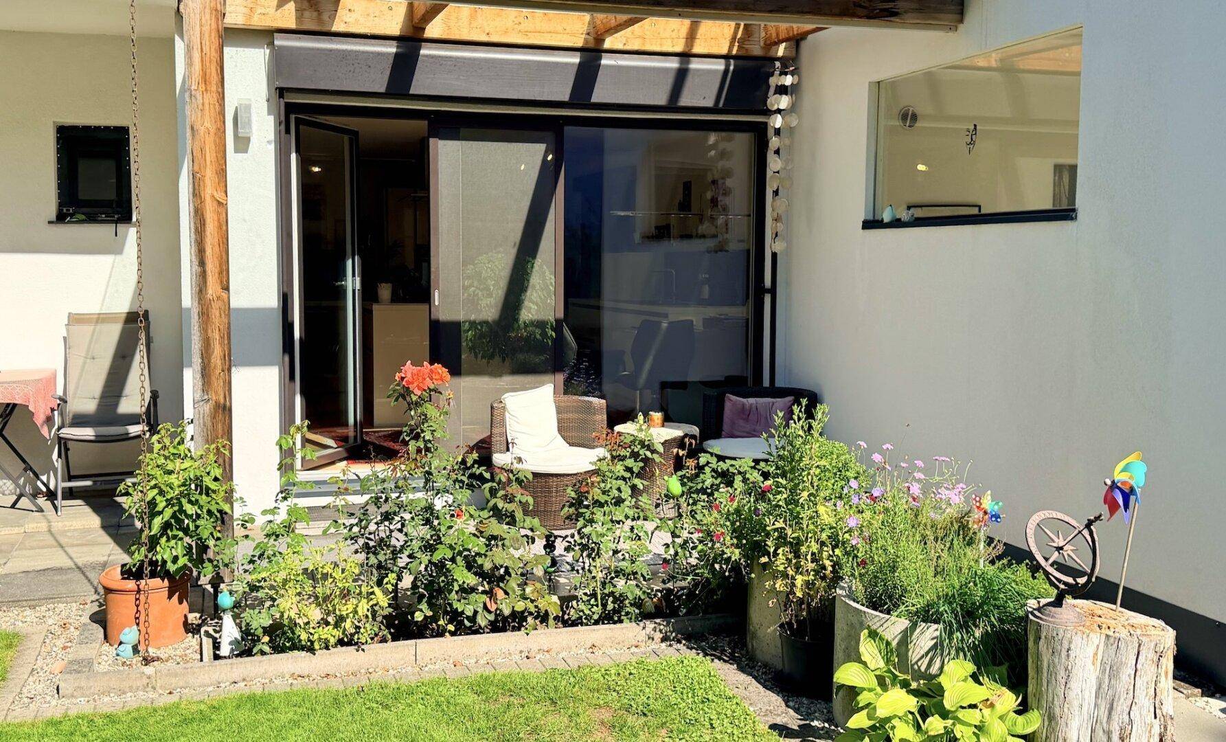 Gemütliche Terrasse mit Pflanzen und Sitzgelegenheiten, direkt am Haus gelegen.