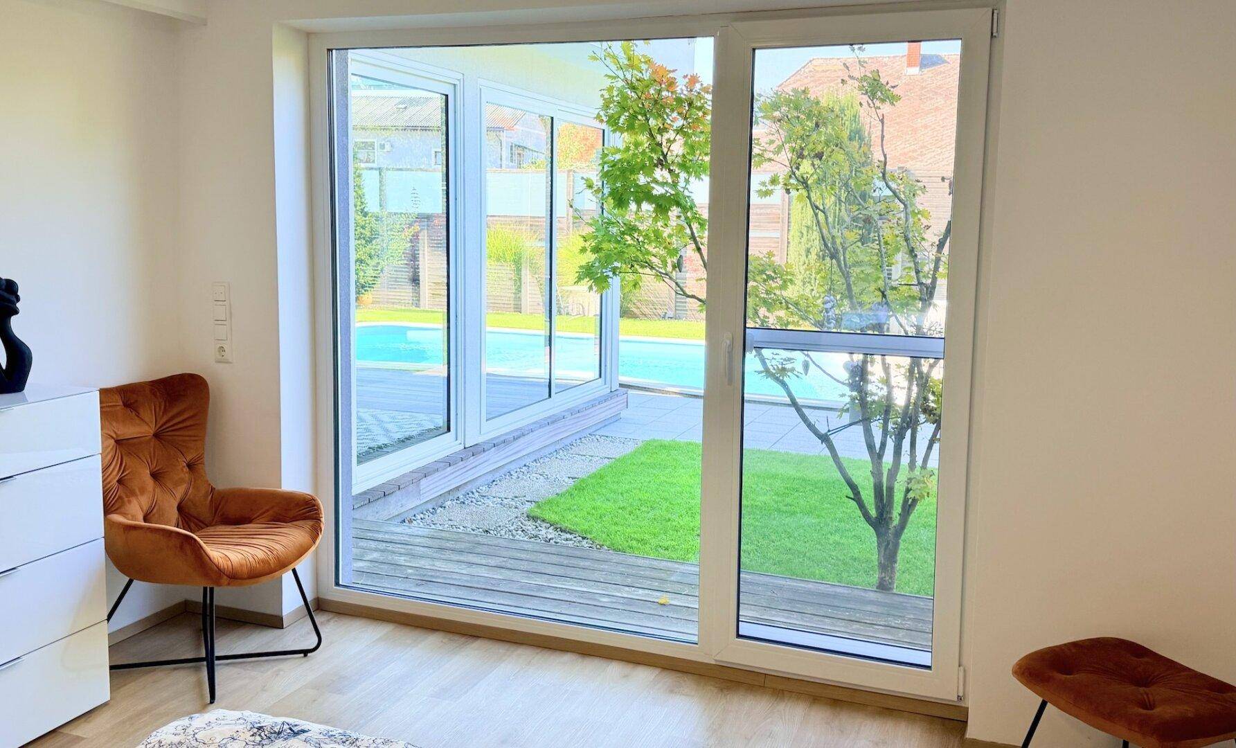 Schlafzimmer mit großen Fenstern, die einen schönen Blick auf den Garten und den Pool bieten.
