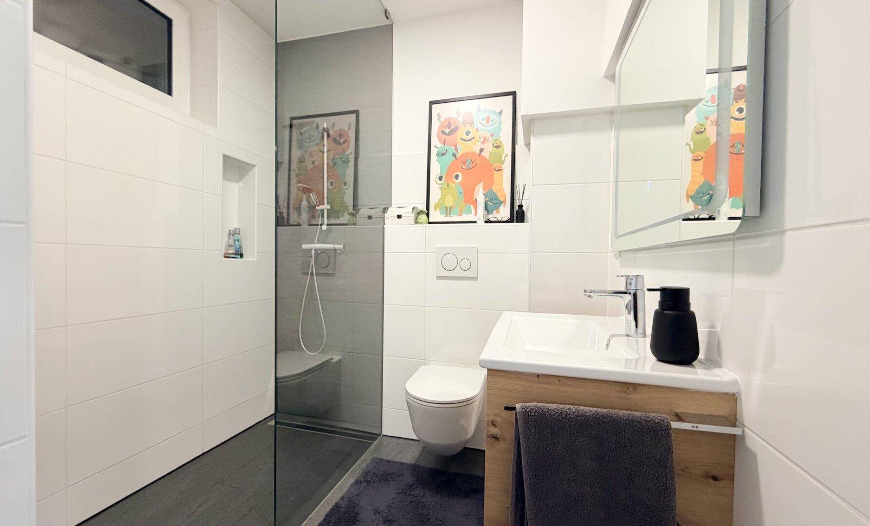 Modernes Badezimmer mit ebenerdiger Dusche, Wand-WC und Holzwaschtisch.