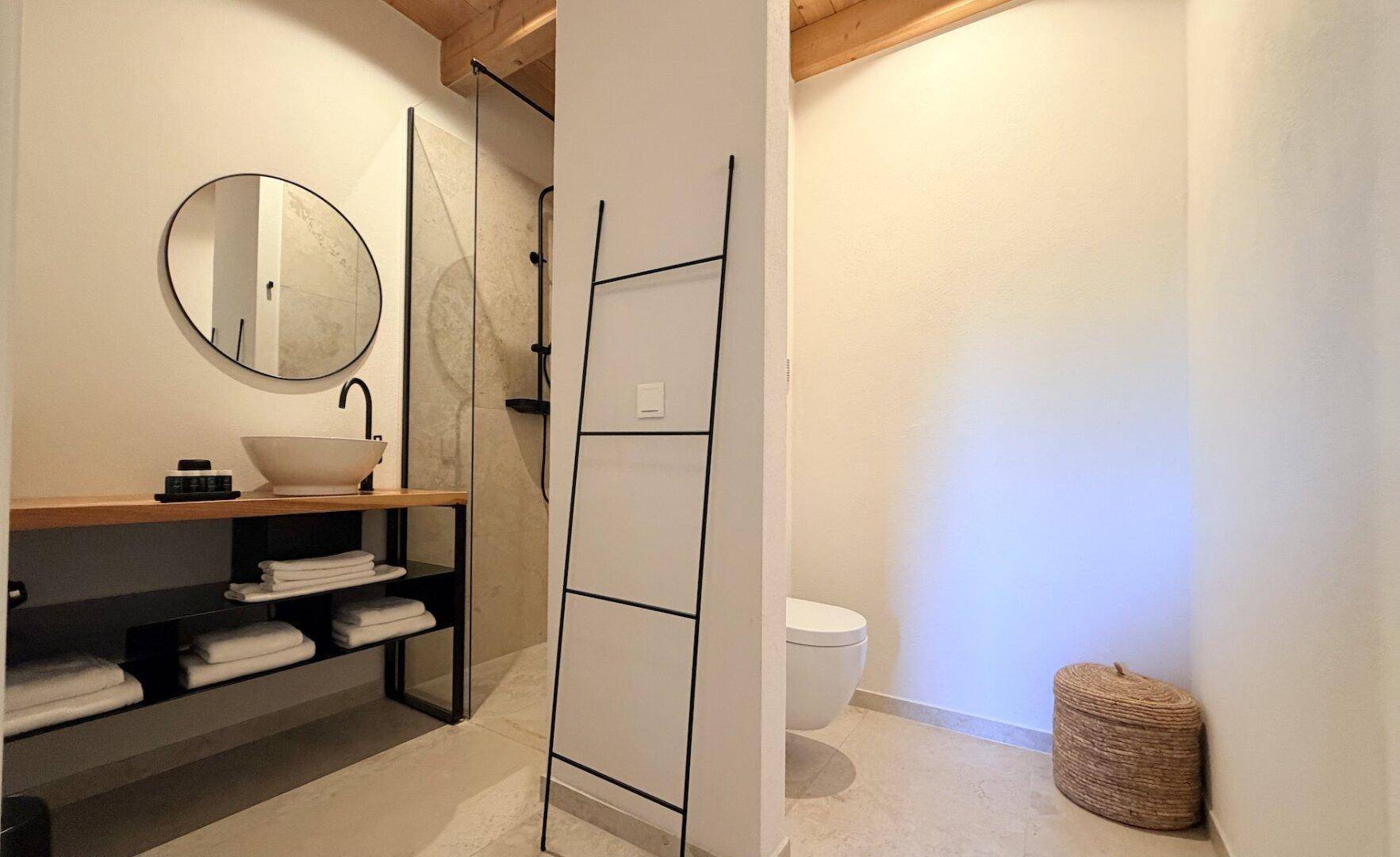 Modernes Badezimmer mit begehbarer Dusche, Aufsatzwaschbecken und minimalistischem Design.