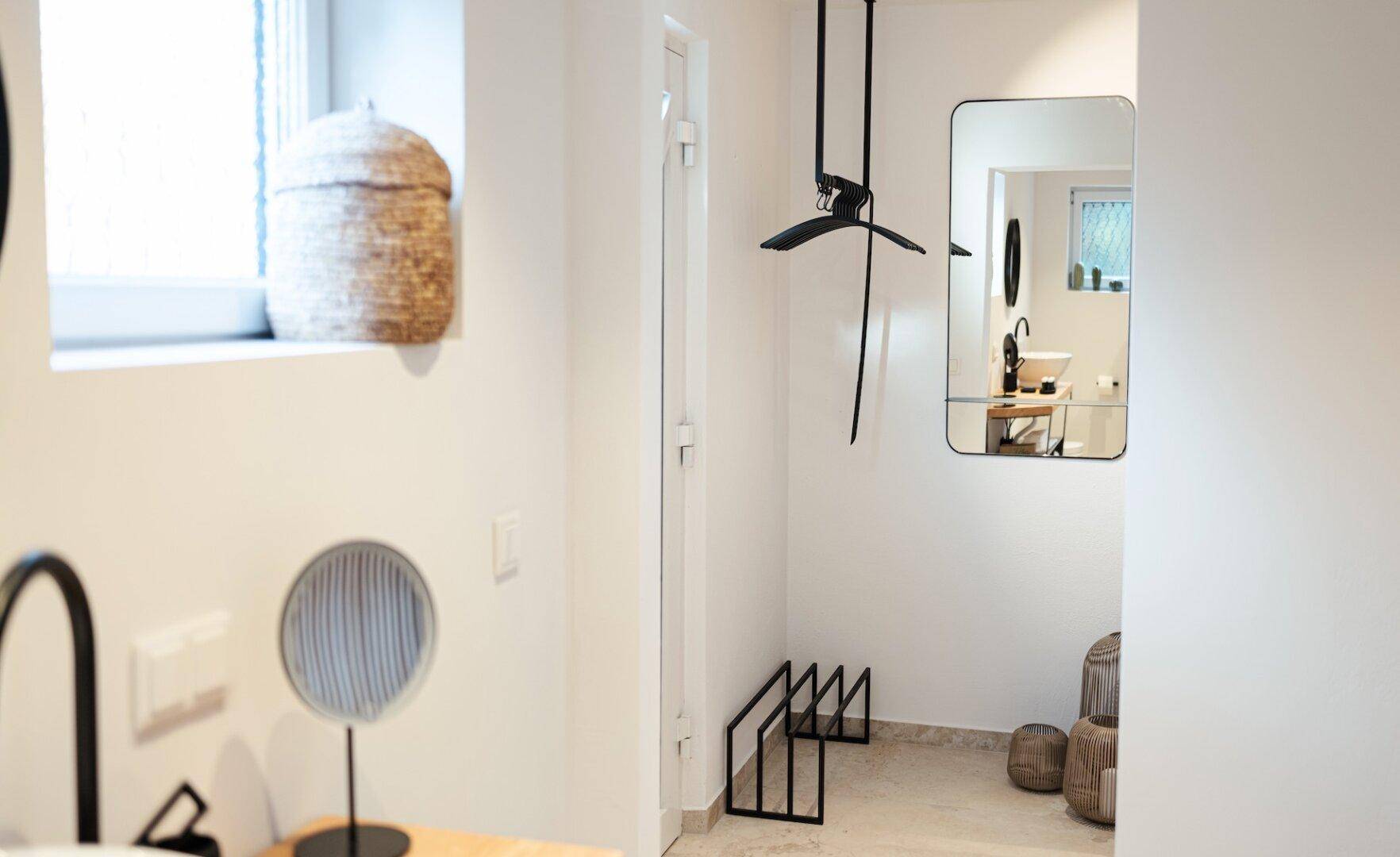 Heller Bereich mit modernem Spiegel, stilvollen Accessoires und Fliesenboden.
