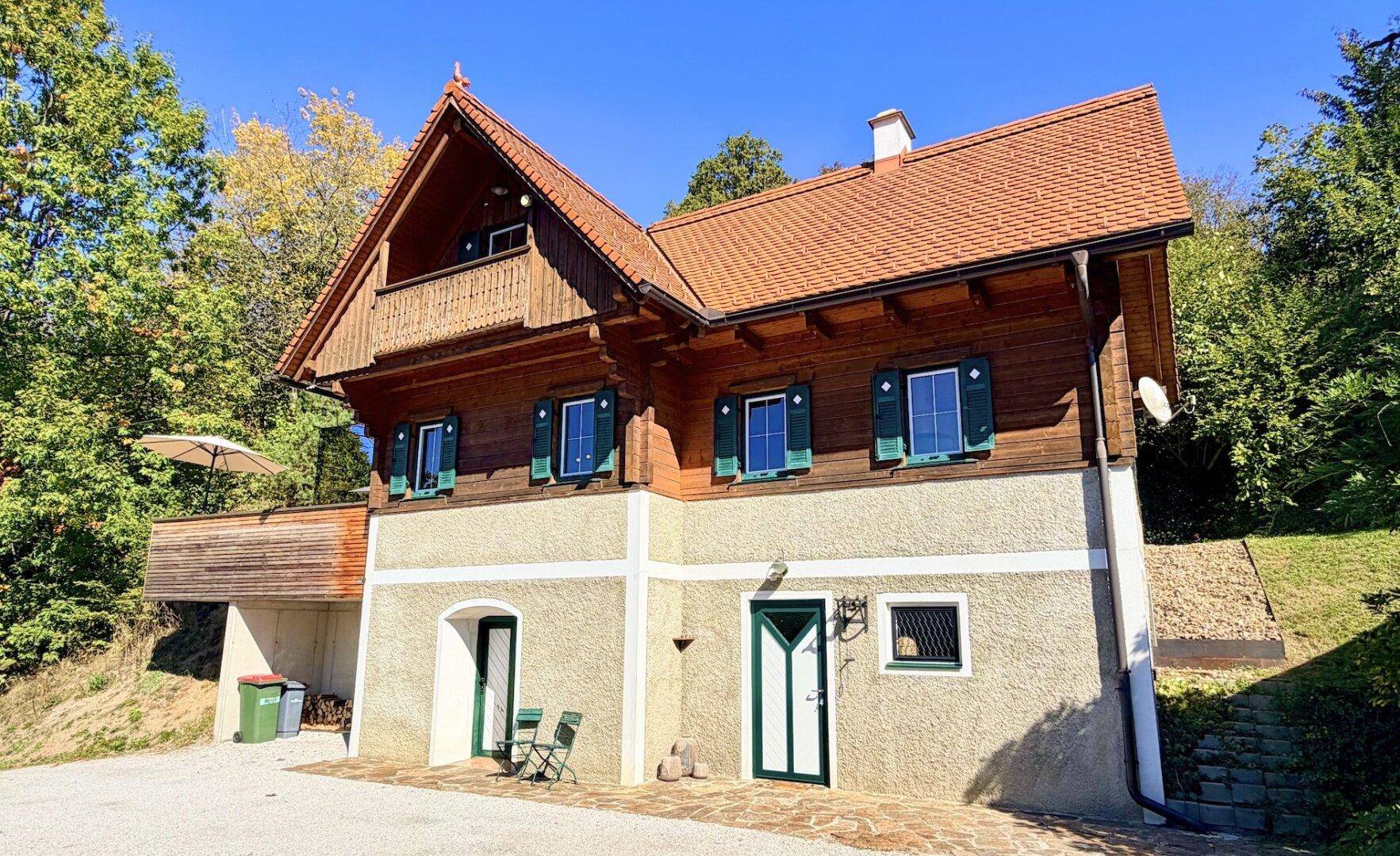 Charmantes Landhaus mit Holzfassade, grünen Fensterläden und traditionellem Satteldach.