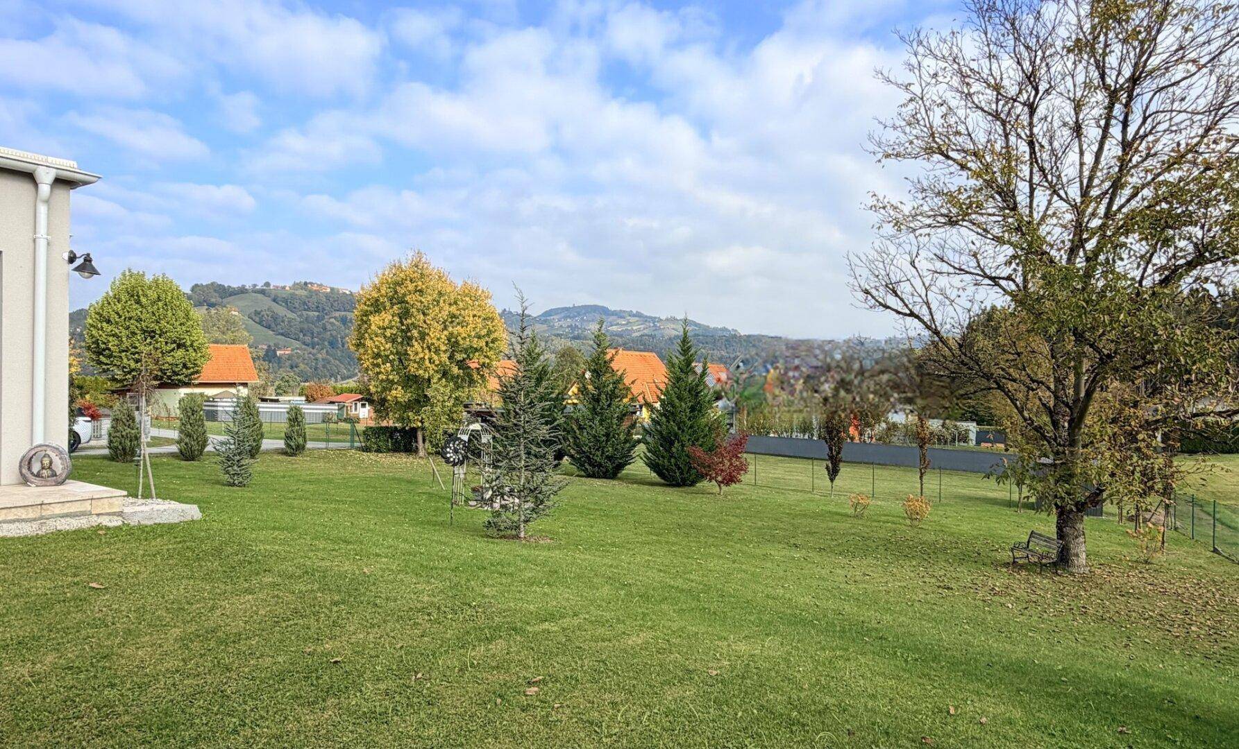 Weitläufiger Garten mit gepflegtem Rasen und Blick auf die hügelige Landschaft im Herbst.