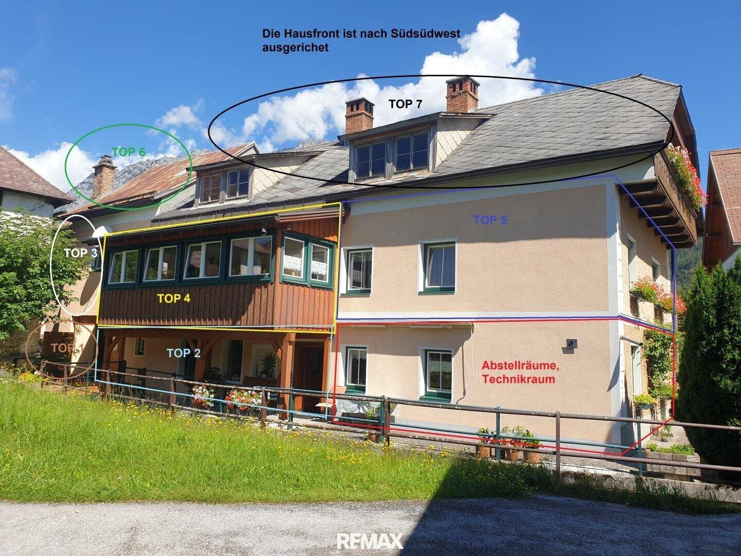 Fassade eines Gebäudes mit mehreren Wohneinheiten und Balkonen, umgeben von Grünflächen.