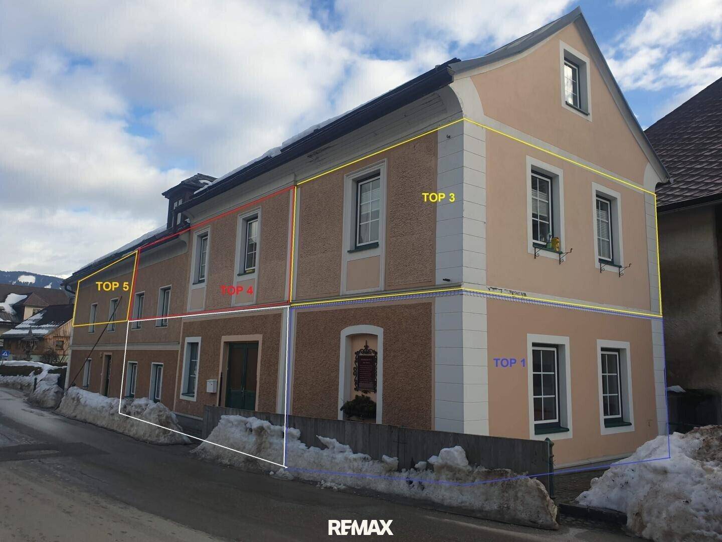 Gebäudefassade im Winter mit Schnee auf dem Boden und klaren Linien der Architektur.