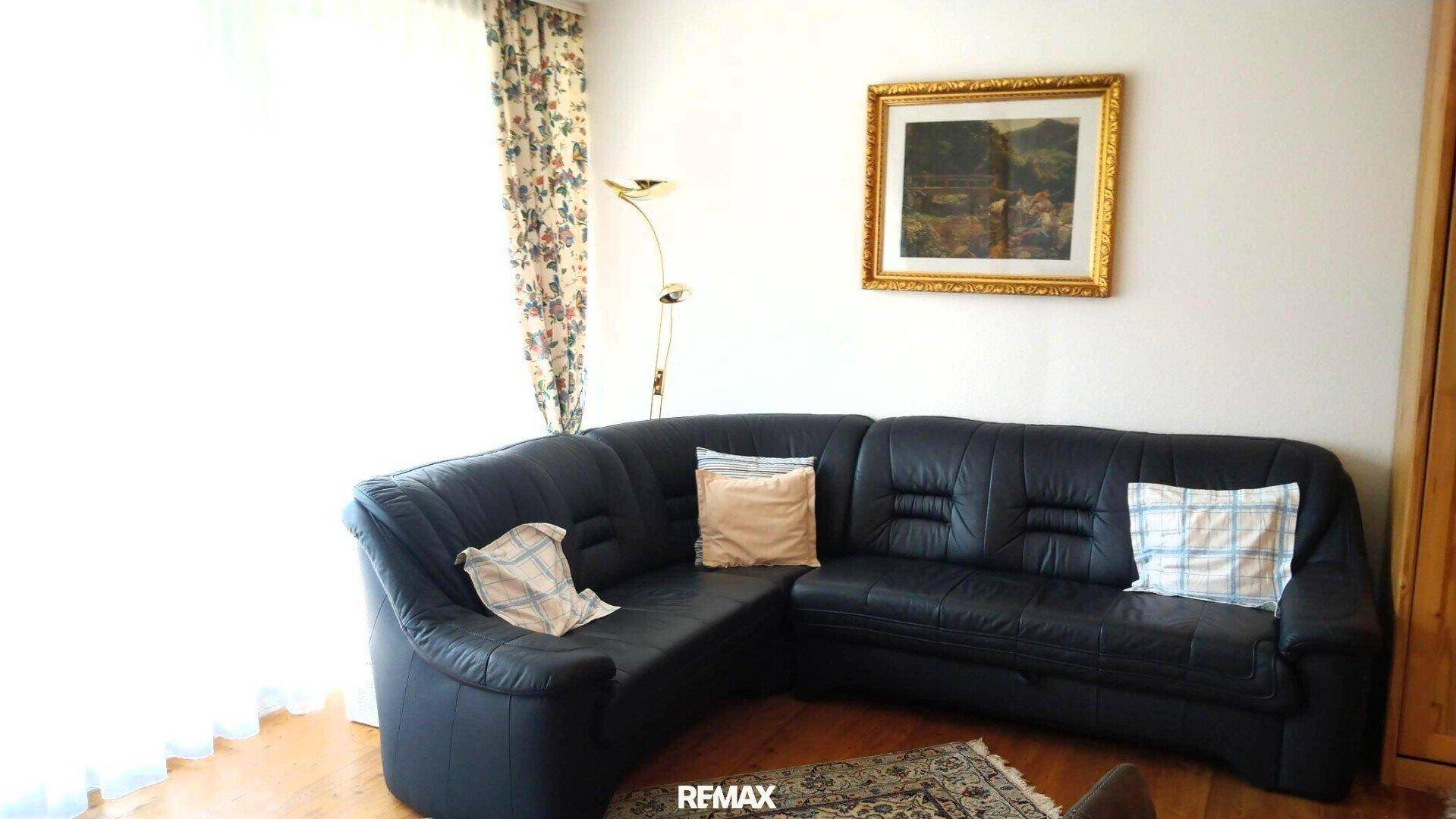 Gemütliches Wohnzimmer mit dunklem Ledersofa und einem gerahmten Gemälde an der Wand.