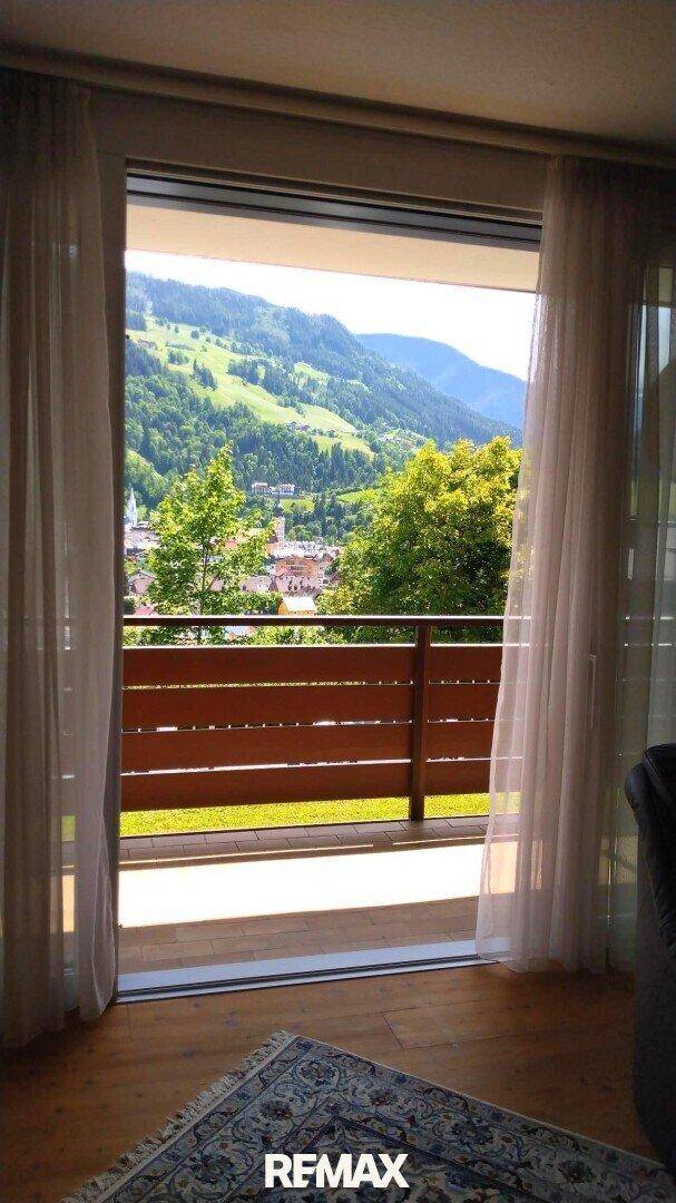 Heller Innenraum mit Zugang zu einem Balkon und weitem Blick auf Berge und Tal.