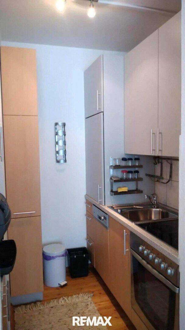 Funktionale Küche mit Spüle, Backofen, Geschirrspüler und hellen Holzschränken.