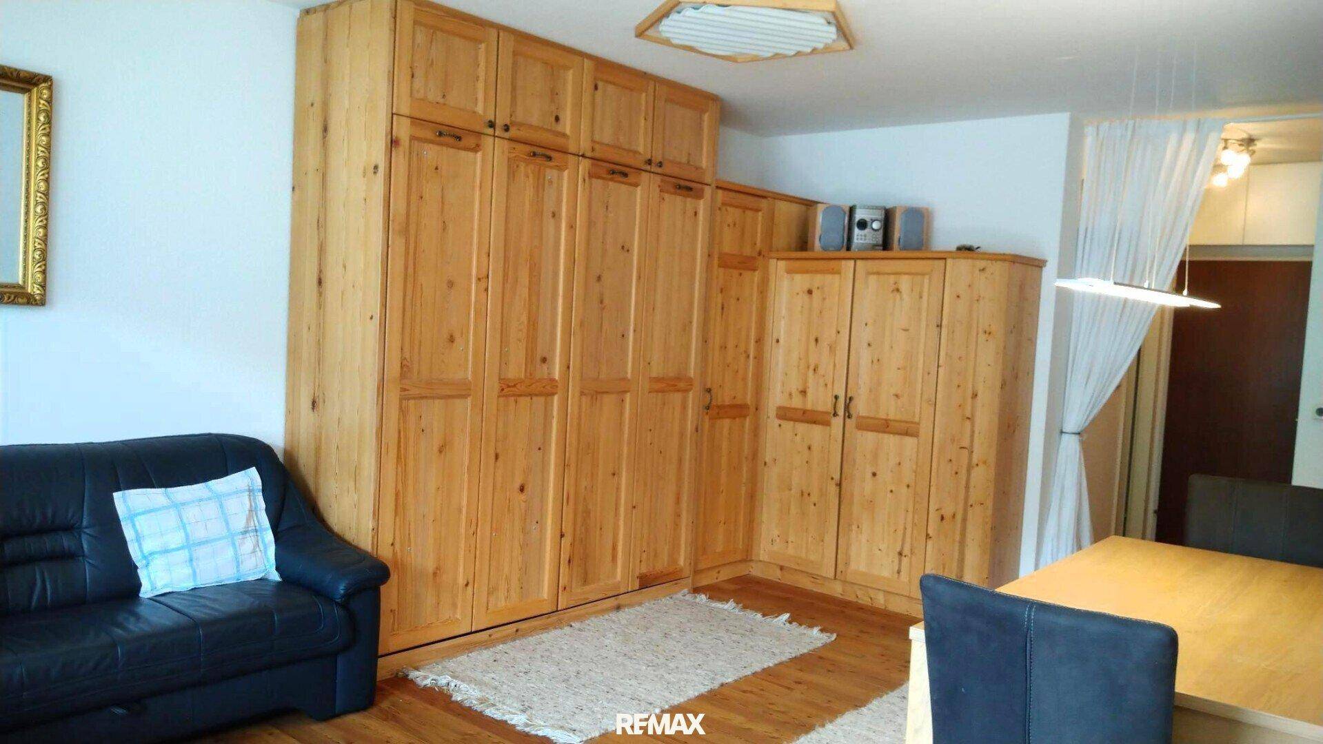 Gemütlicher Wohnbereich mit großem Einbauschrank aus Holz und dunklem Ledersofa.
