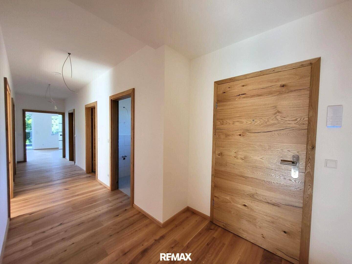 Heller Flur mit Echtholzboden und modernen Holztüren, der zu weiteren Räumen führt.