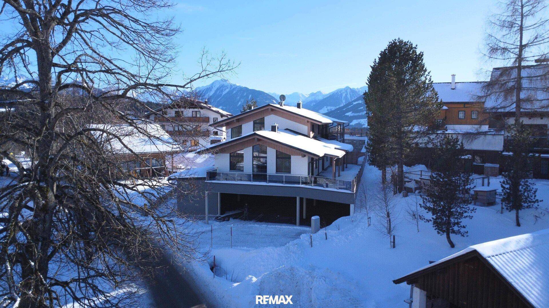 Winteransicht des modernen Hauses in verschneiter Berglandschaft mit klarem Himmel.