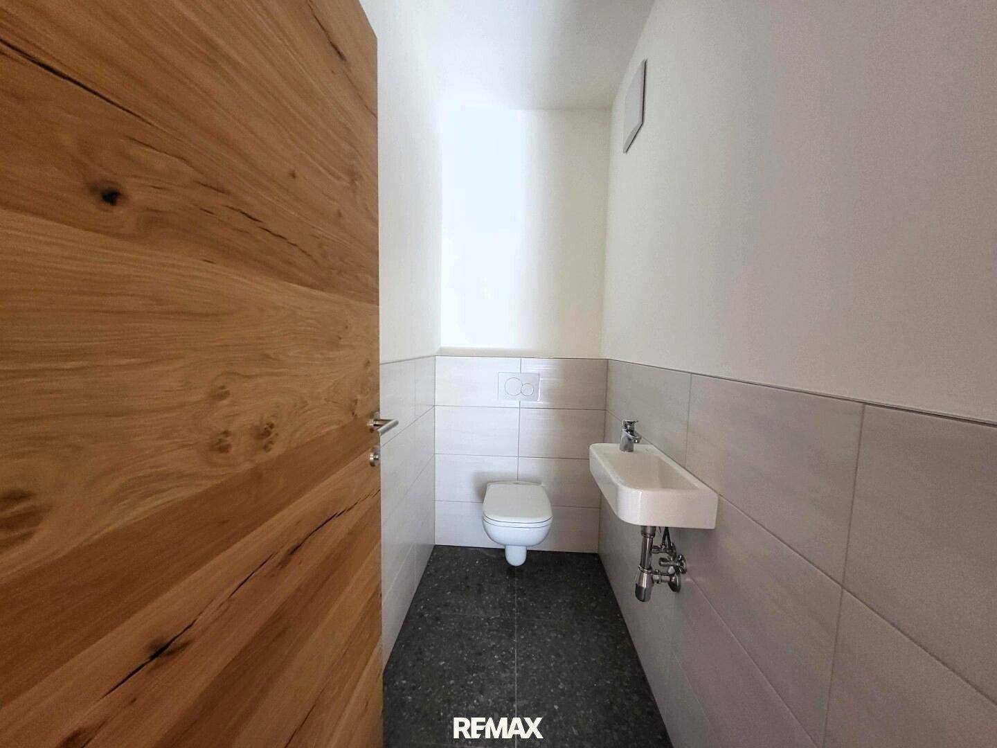 Kleines Gäste-WC mit modernem Waschbecken und Wand-WC, hell gefliest.