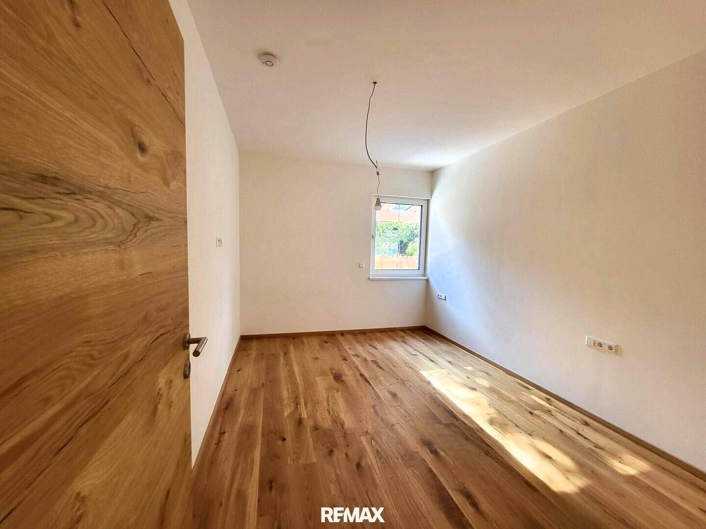 Freundliches Zimmer mit Holzboden und einem Fenster, das den Raum gut belichtet.