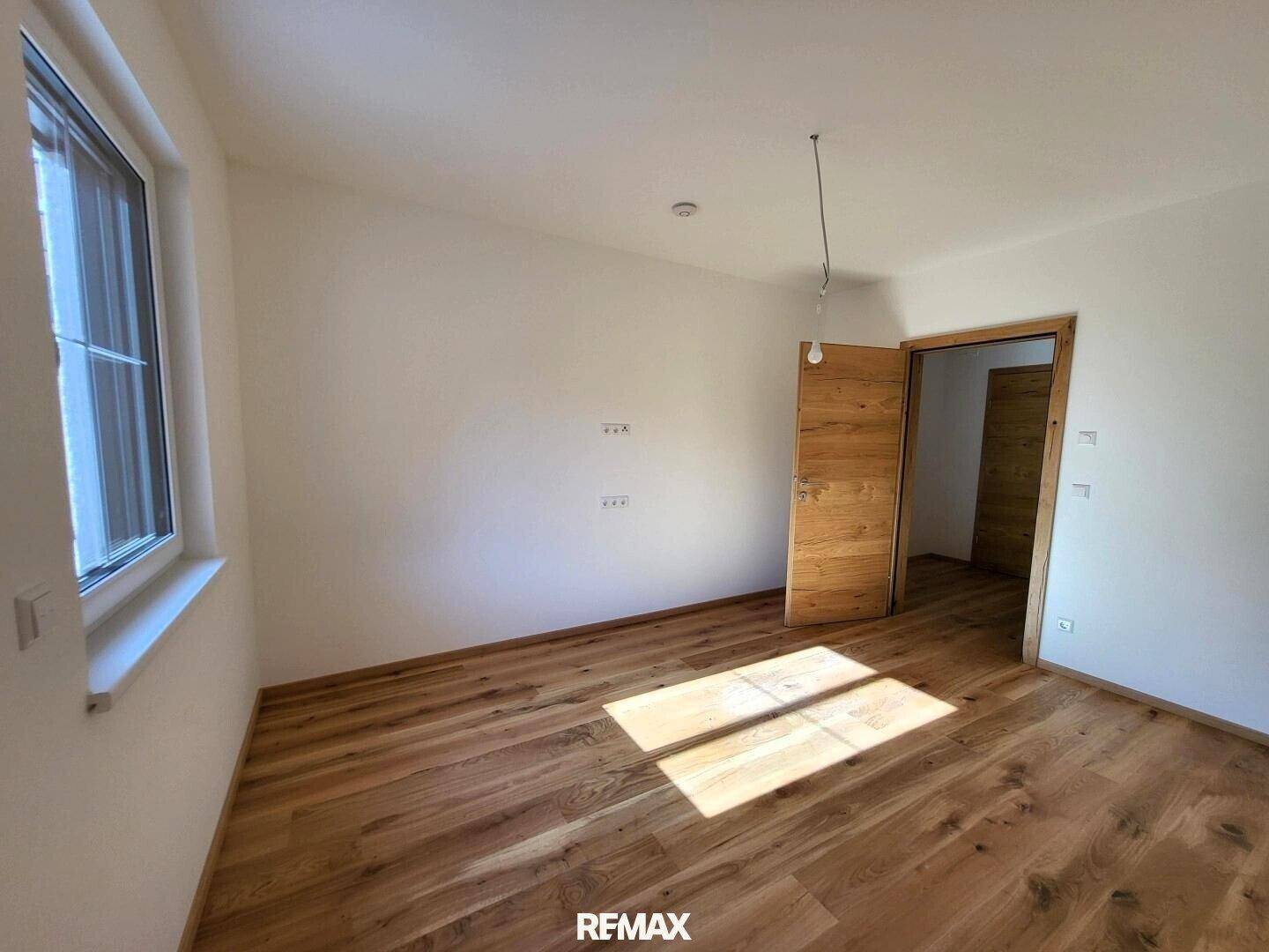 Helles Zimmer mit Holzboden und einem Fenster, das viel Tageslicht hereinlässt.