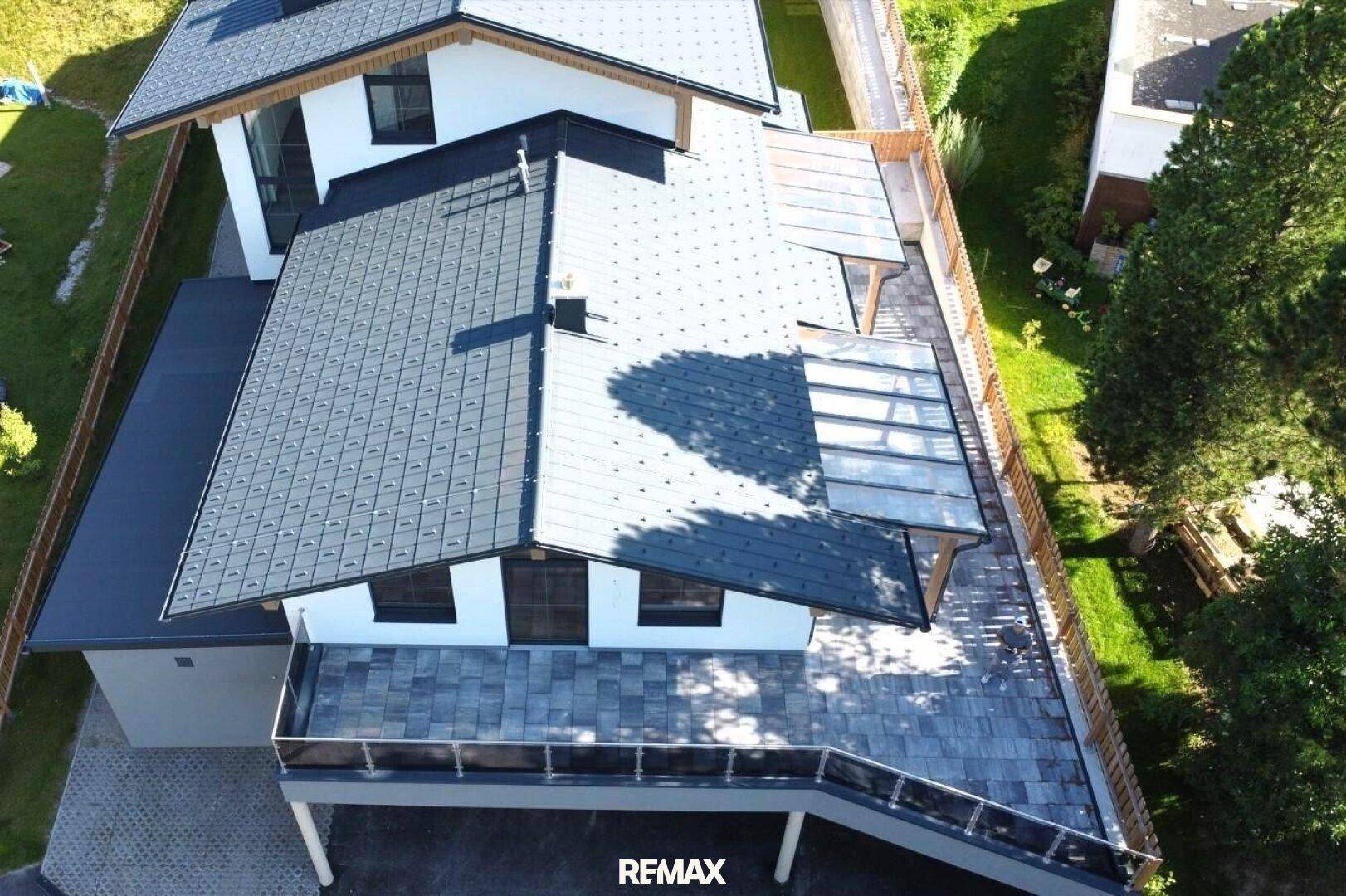 Dachansicht eines modernen Hauses mit großzügiger Terrasse und Photovoltaik-System.