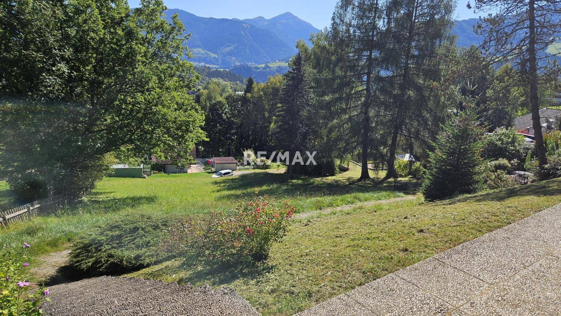 Großer Gartenbereich mit Rasen, Bäumen und Blick auf die umliegende Hügellandschaft.