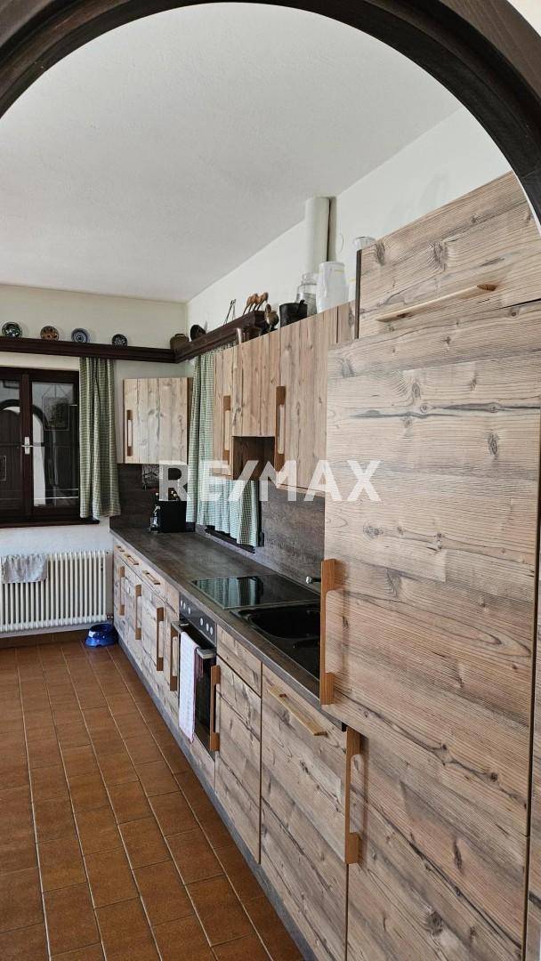 Rustikale Küche mit Holzfronten, dunkler Arbeitsplatte und integrierten Geräten.