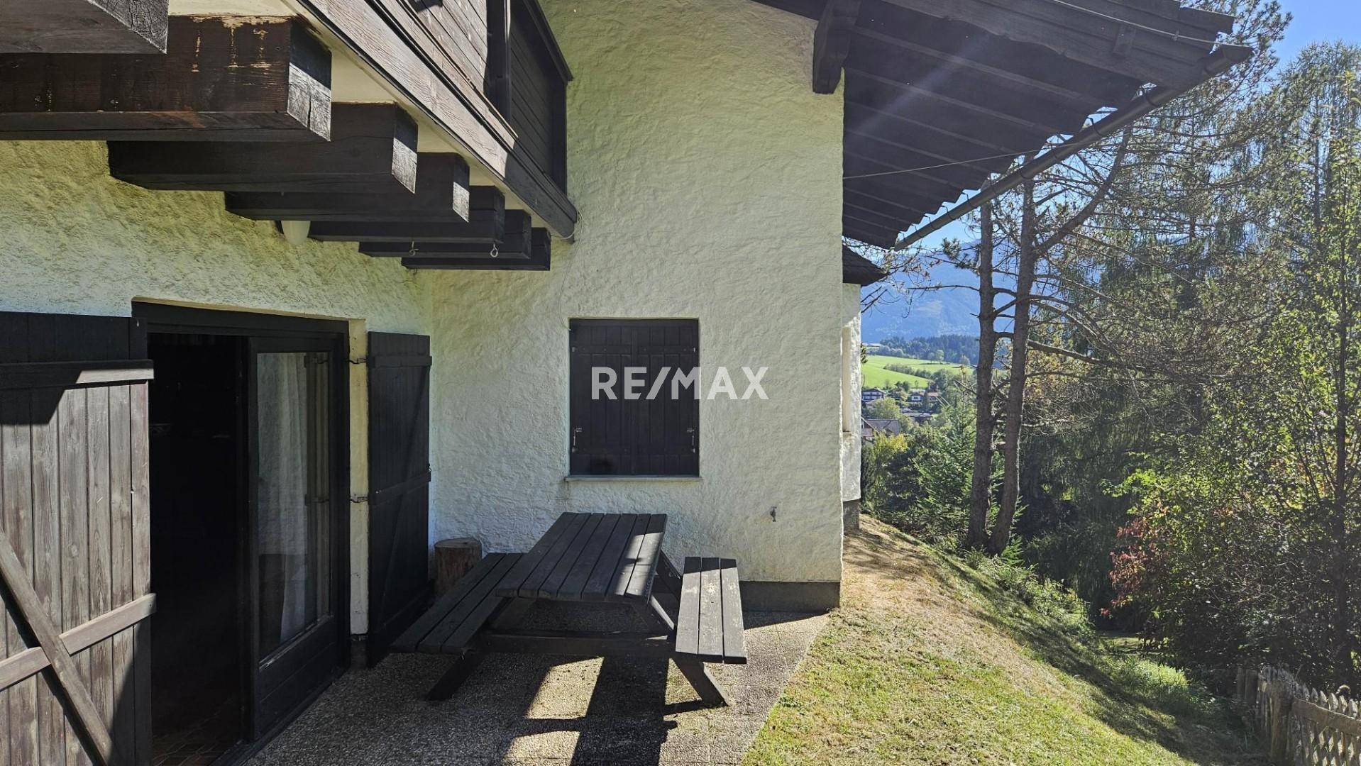 Kleine Terrasse mit Picknicktisch und Zugang zum Garten, umgeben von Natur.