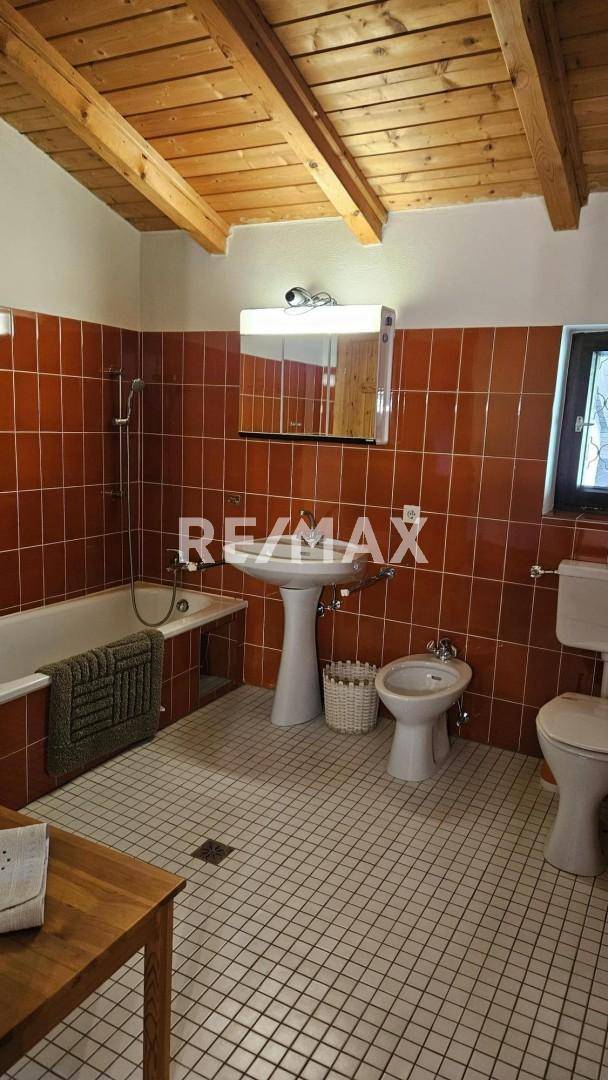 Badezimmer mit roten Fliesen, Badewanne, Bidet und Waschbecken.