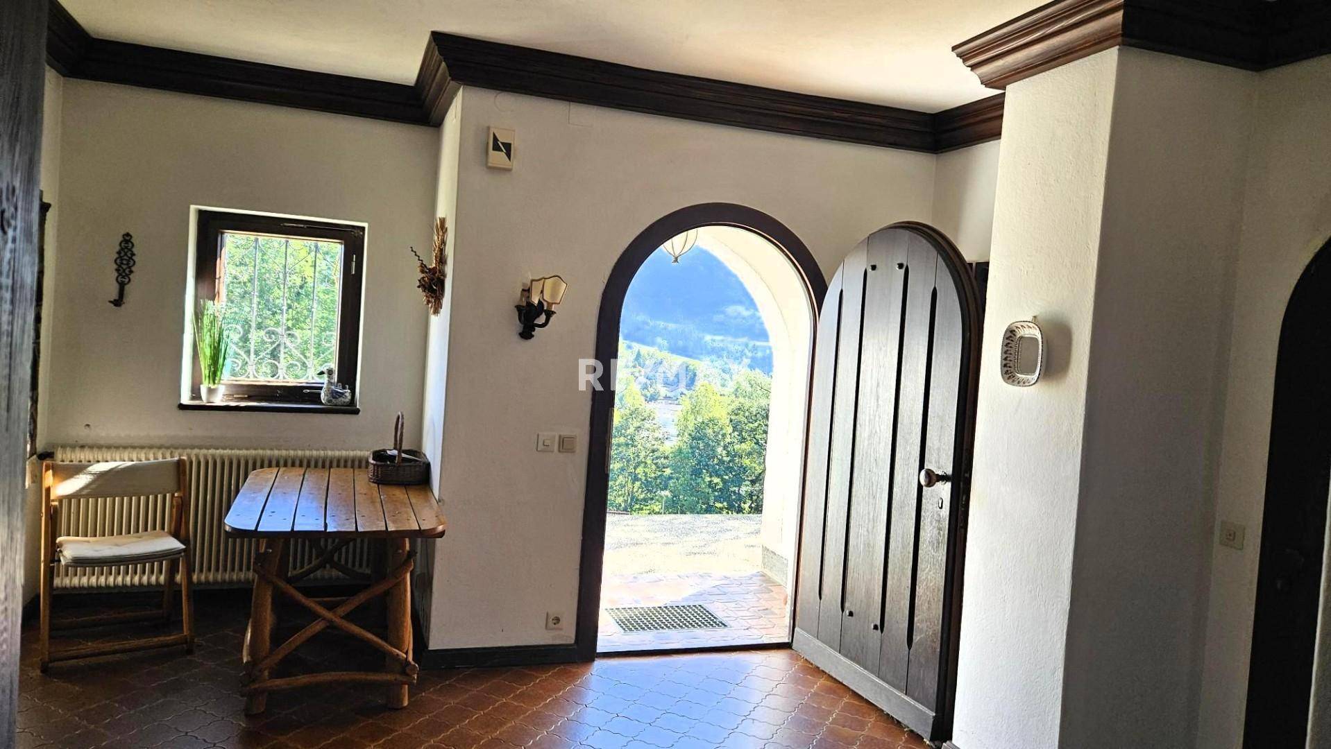 Heller Eingangsbereich mit offener Holztür, die einen weiten Blick ins Grüne bietet.