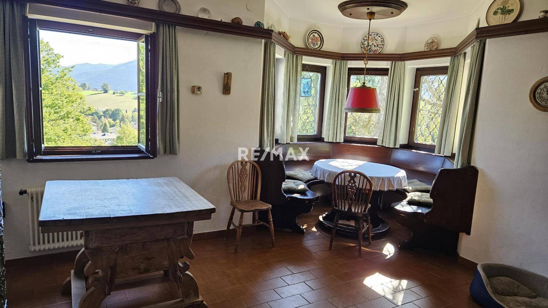 Rustikaler Essbereich mit Erkerfenstern, Holztisch und Blick auf die umliegende Landschaft.