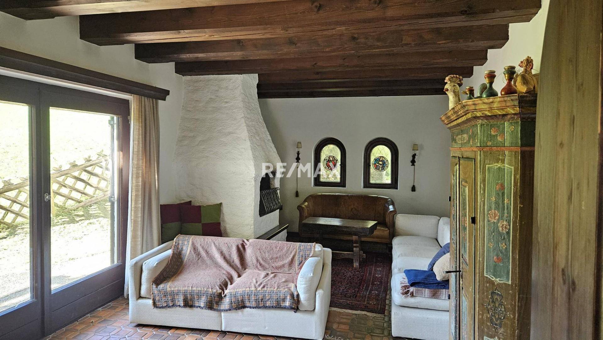 Gemütliches Wohnzimmer mit Kamin, Holzbalkendecke und Zugang zur Terrasse.