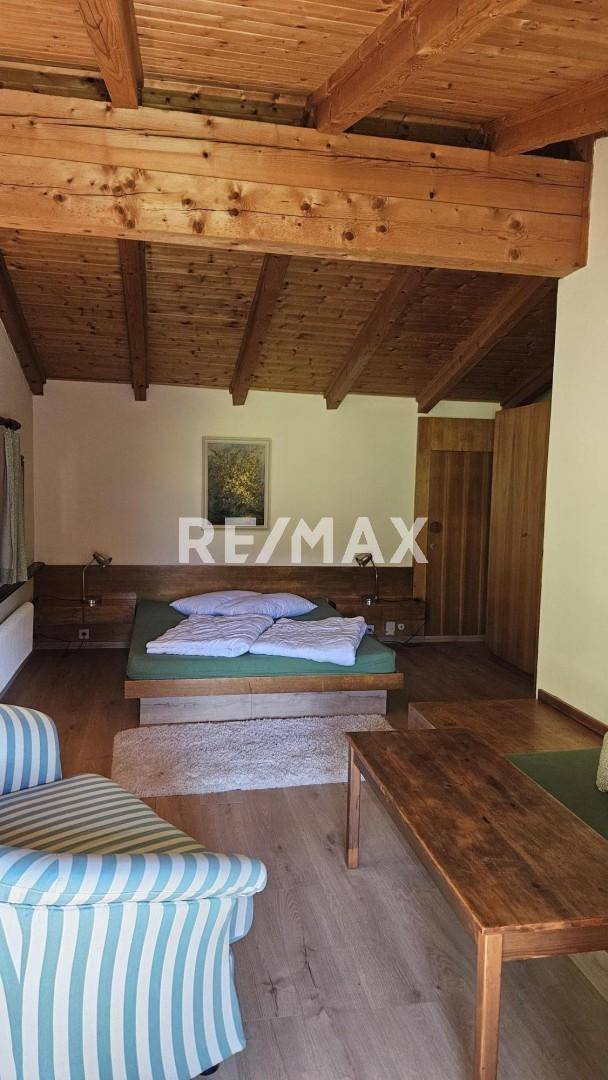 Geräumiges Schlafzimmer mit Holzbalkendecke, Doppelbett und rustikalen Holzmöbeln.