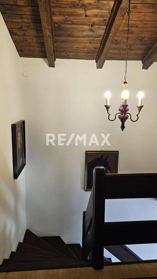 Treppenhaus mit rustikalen Holzstufen und Holzbalkendecke, führt zu den oberen Etagen.